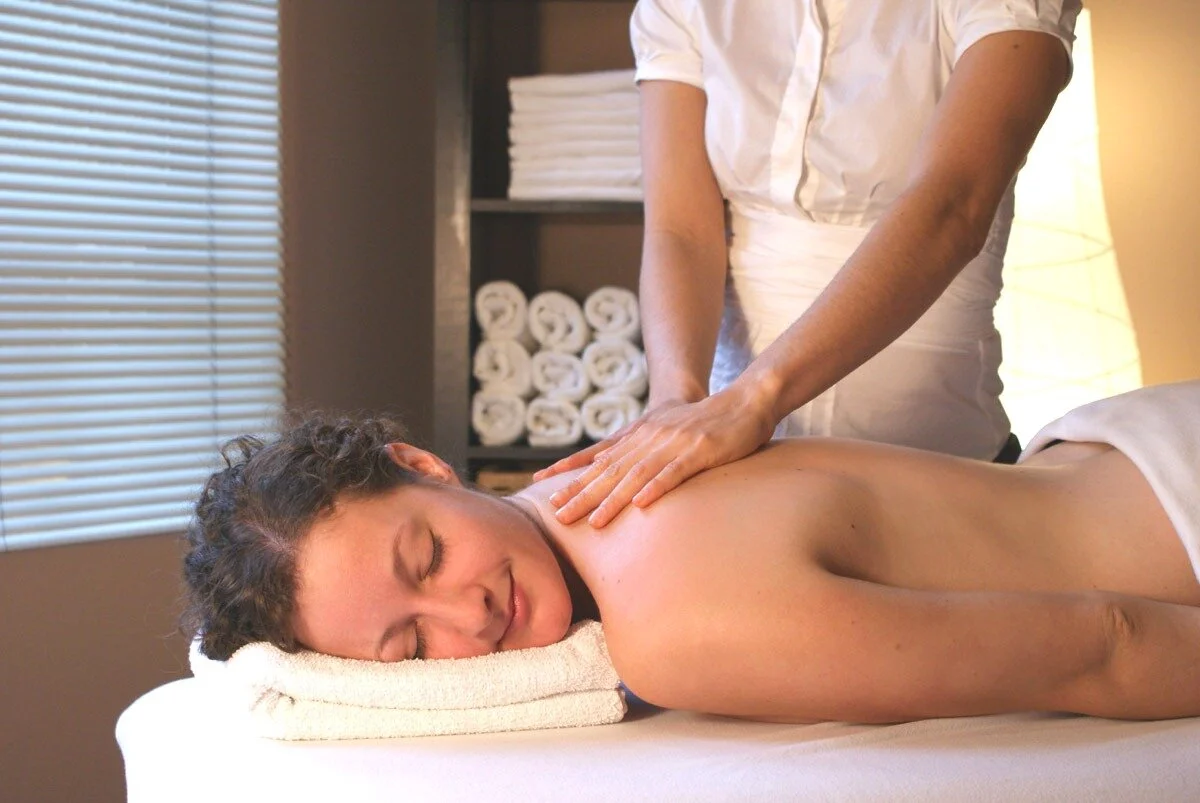 Woman lying face down receiving a professional back and shoulder massage.
