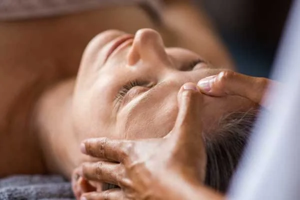 Femme recevant un soin manuel au niveau de la tête et du visage, illustrant les soins en polarité proposés par Zeina Raya à Ville-Émard, Montréal.