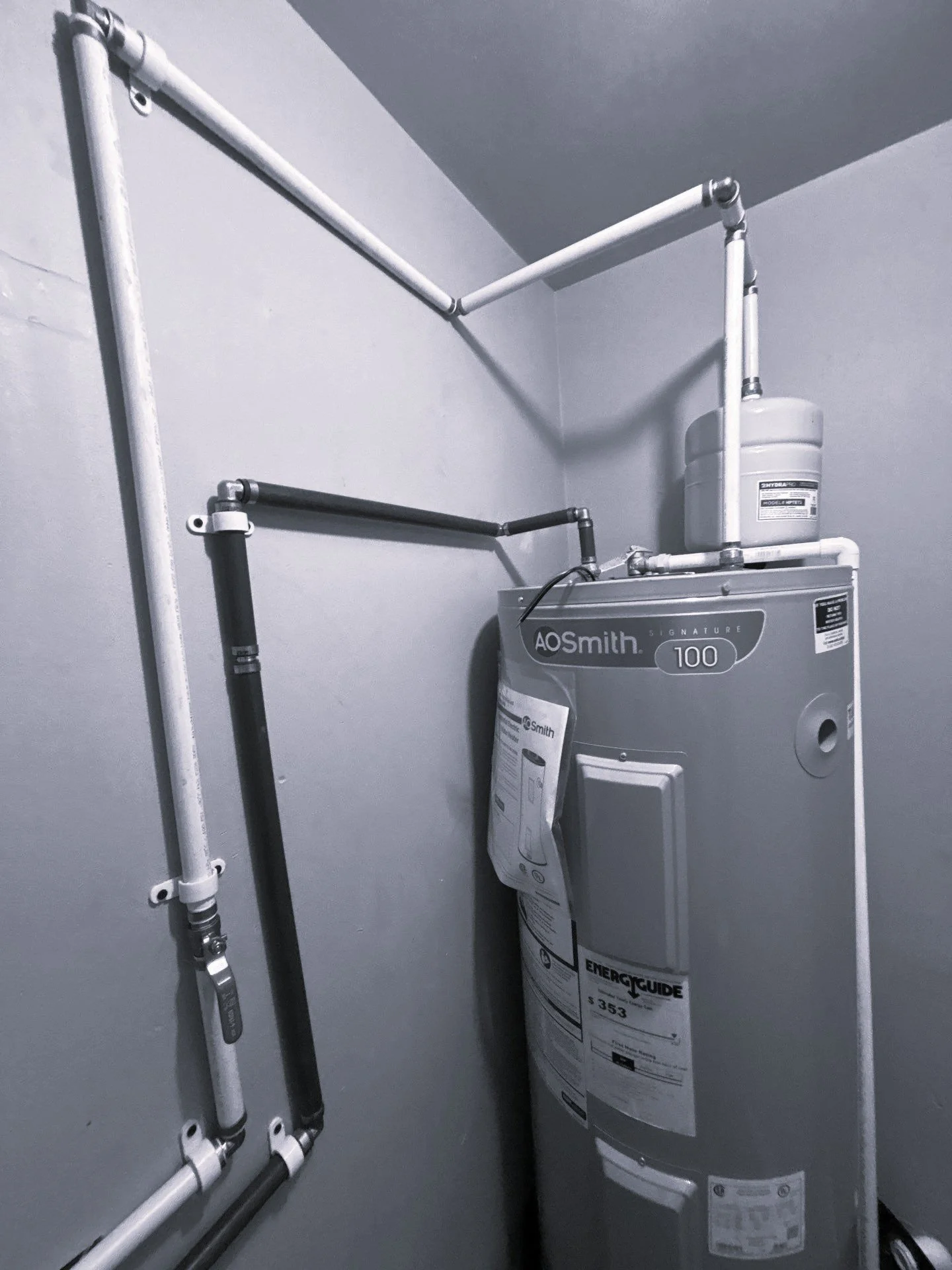 A water heater mounted on a wall with pipes and a gas line connected, with the brand name 'AOSmith' visible on the unit.