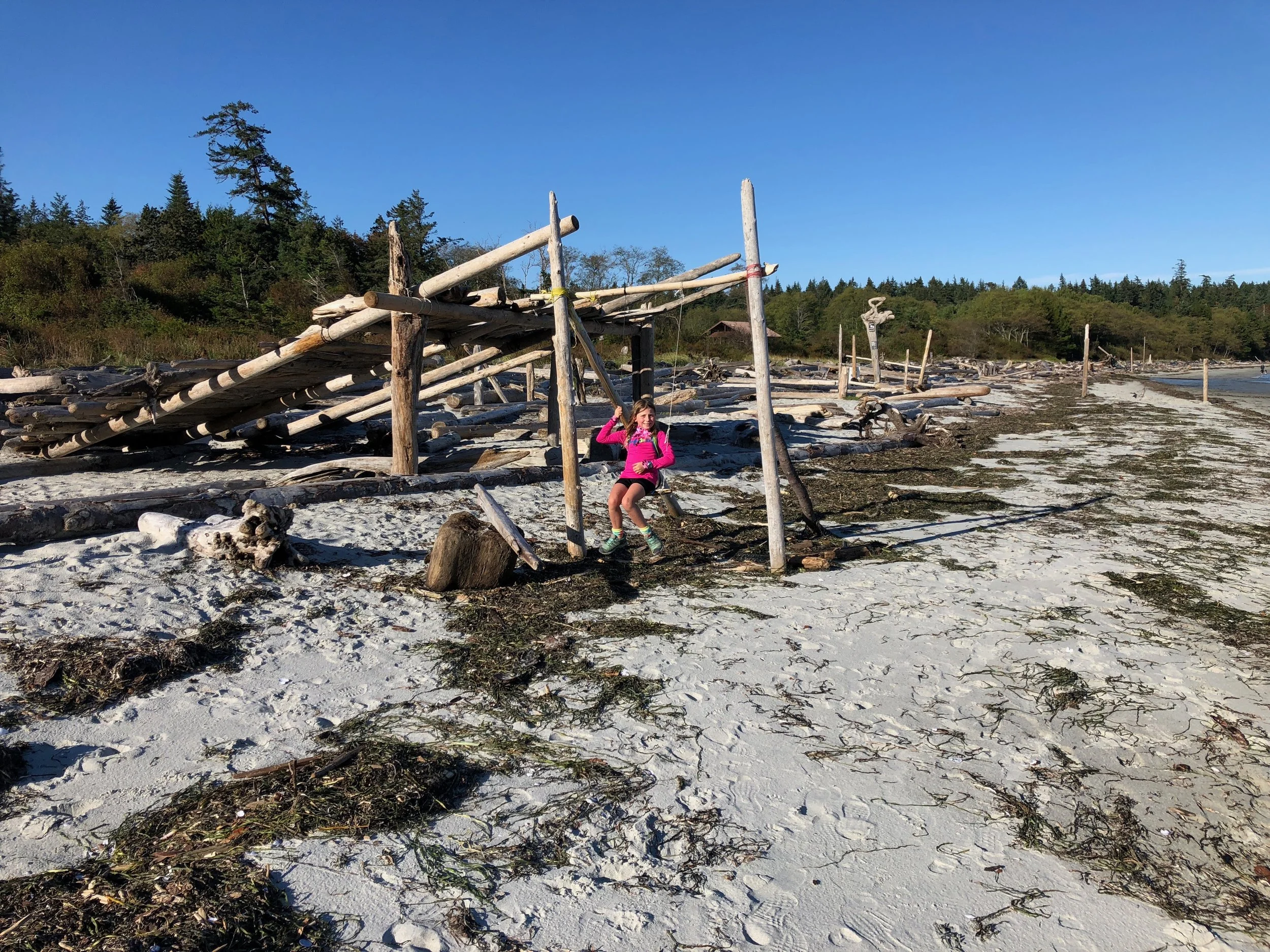 Isla swinging on a swing made from driftwood logs
