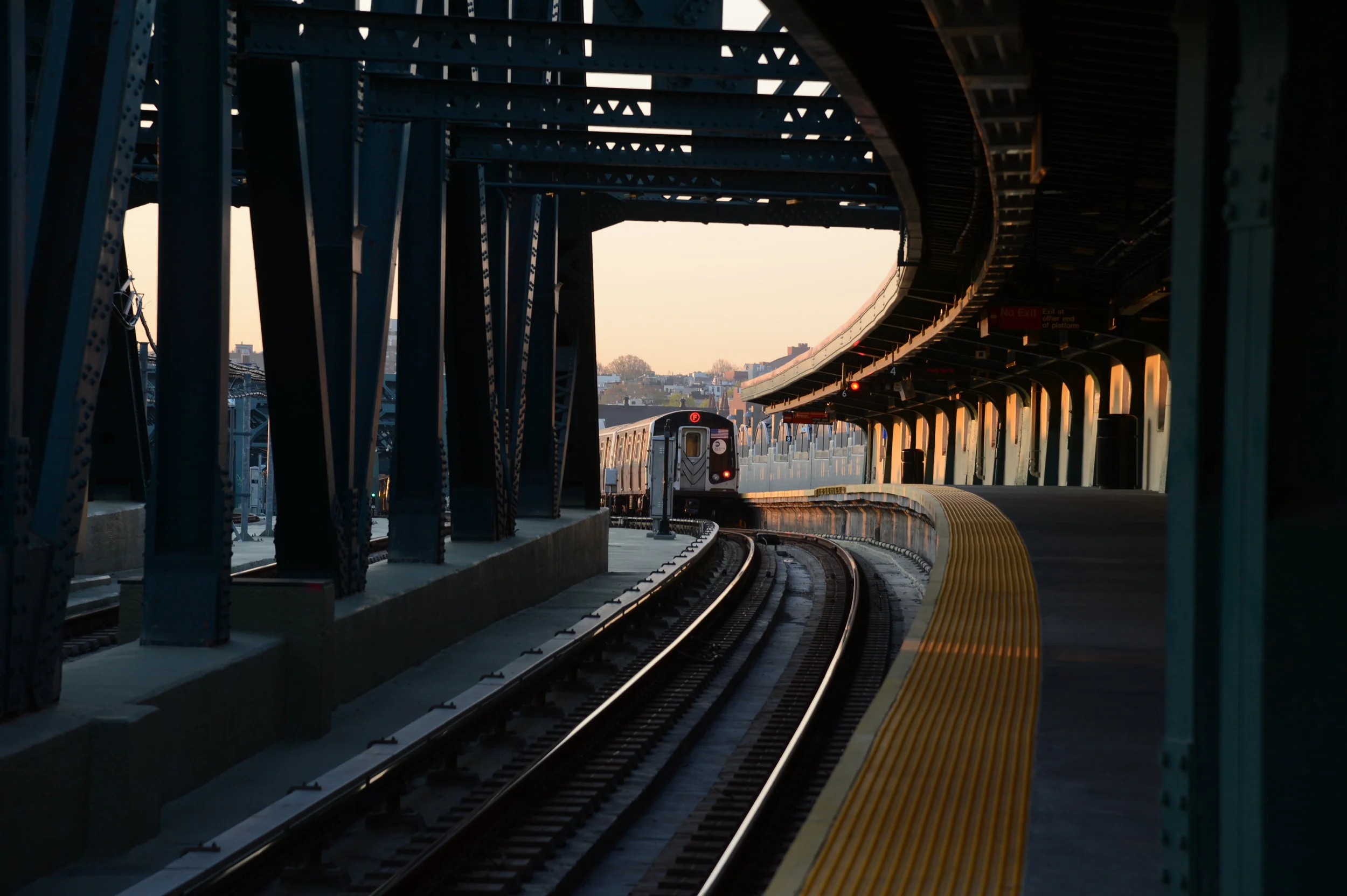 A photo of a subway train pulling into an above-ground station.