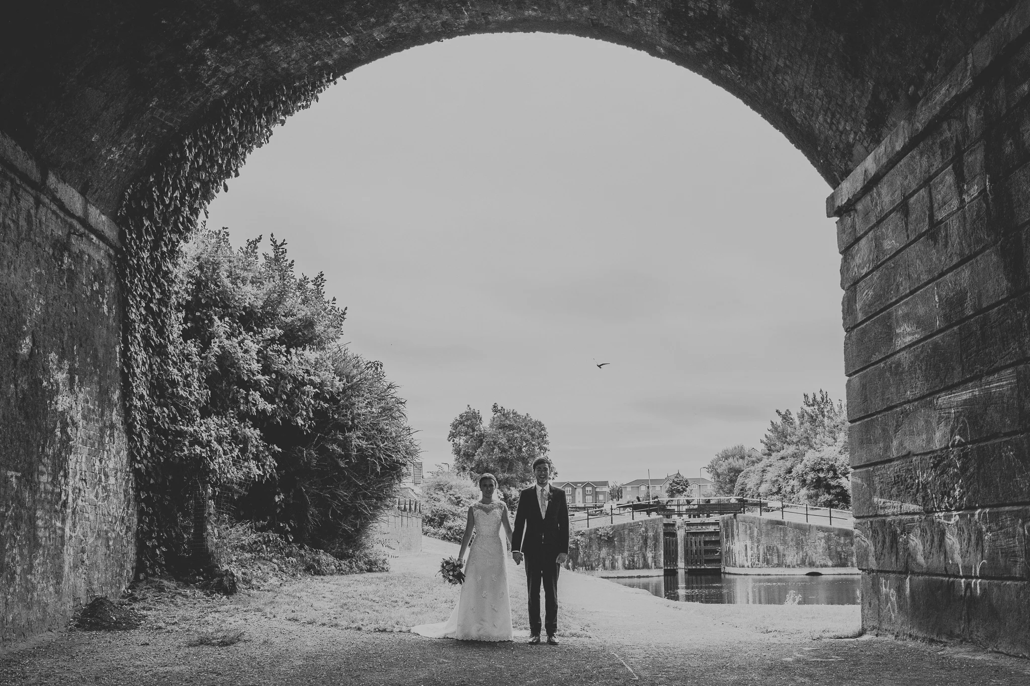 Jess and Ben - Liverpool wedding - bride and groom under a bridge holding hands