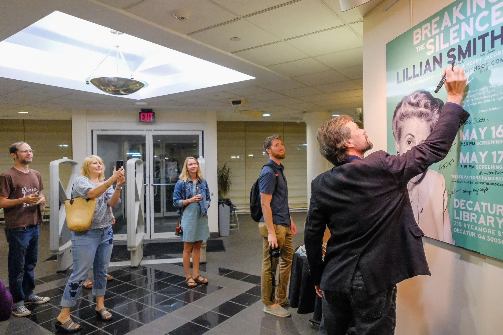 Filmmakers Hal Jacobs (with marker) and Henry Jacobs (looking on, camera in hand) at Decatur Library premiere screening.