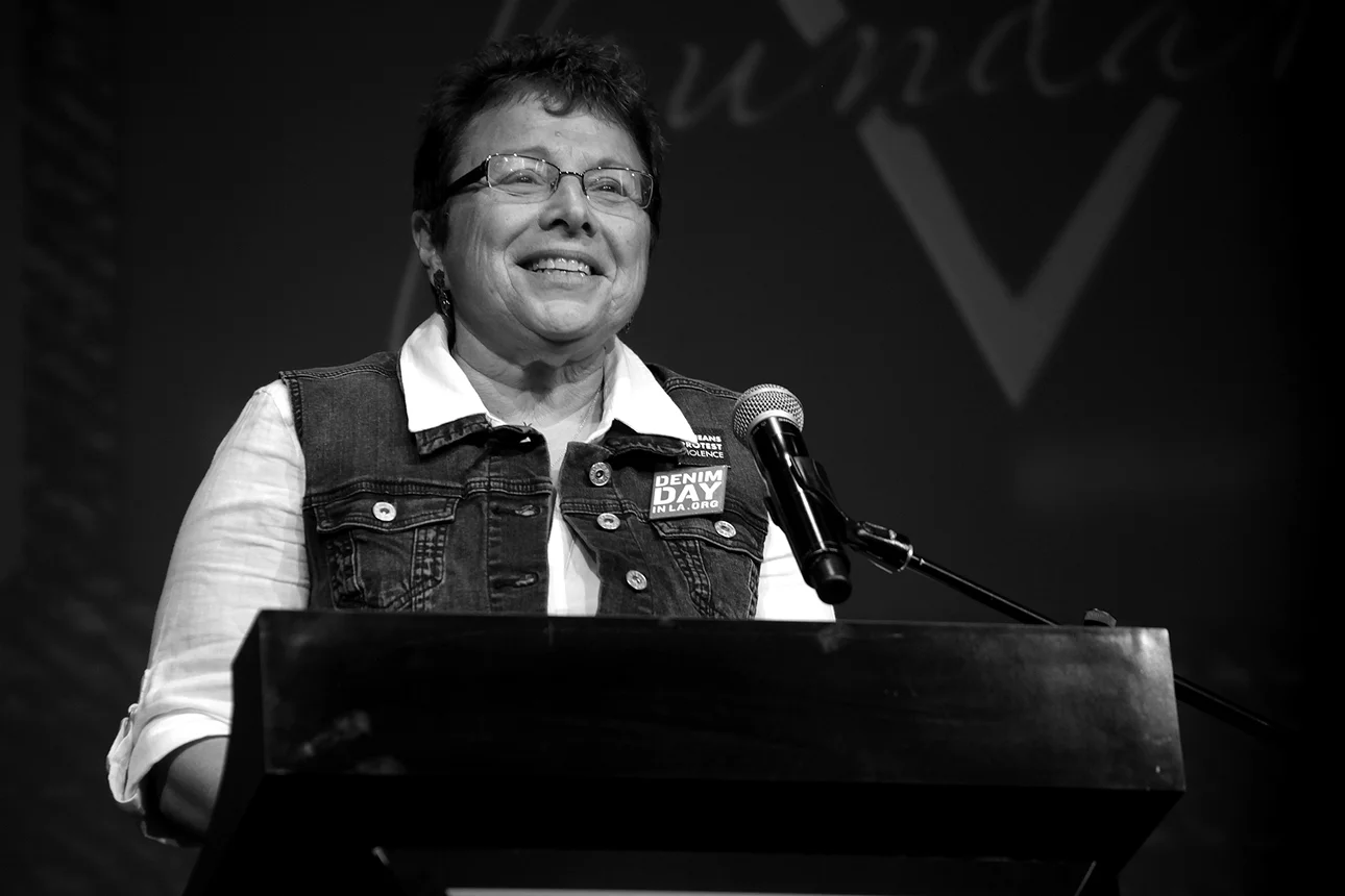 Denim Day Founder and Peace Over Violence Executive Director, Patti Giggans speaks on stage at the GUESS? Inc. Headquarters