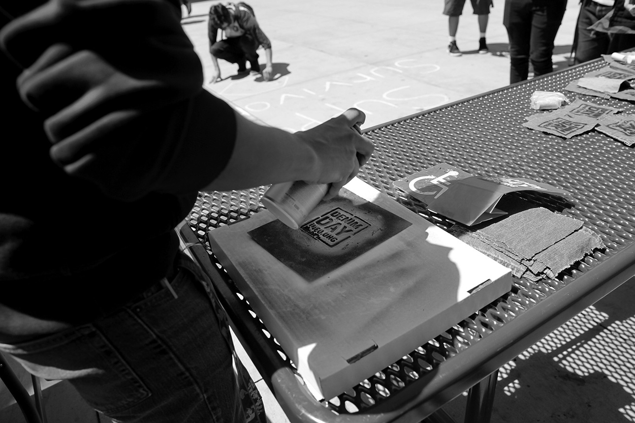  Students spray painting Denim Day stencils on jean pockets 