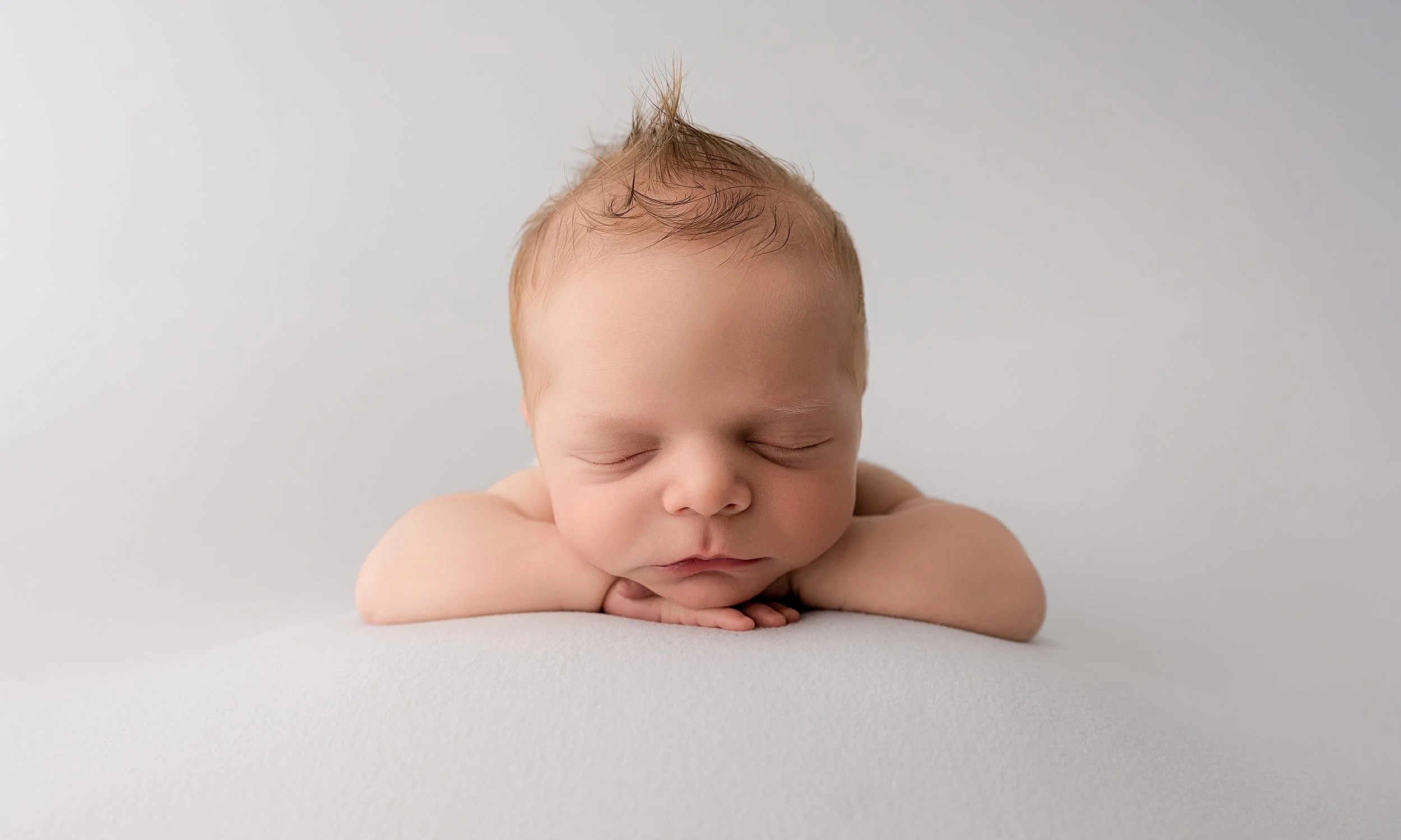 chin on hands pose of baby boy at his newborn photography session in Evans, ga
