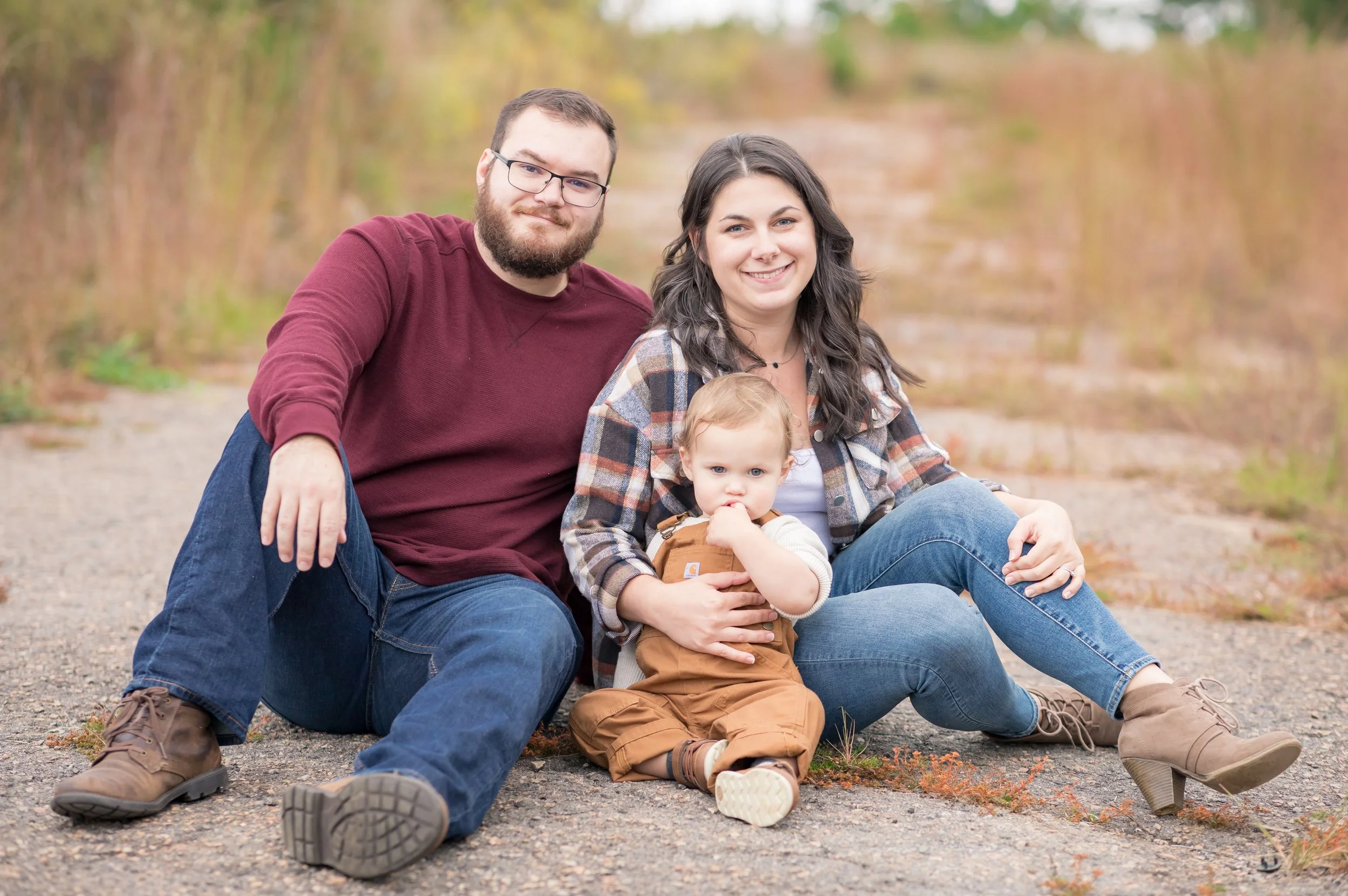Family standing on castle bridge with castle and autumn trees in background.