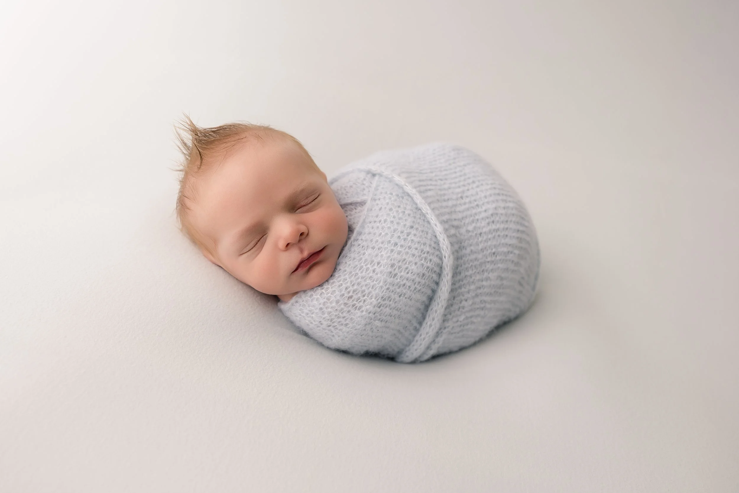 newborn baby boy wrapped laying during his newborn photography session in Evans, GA