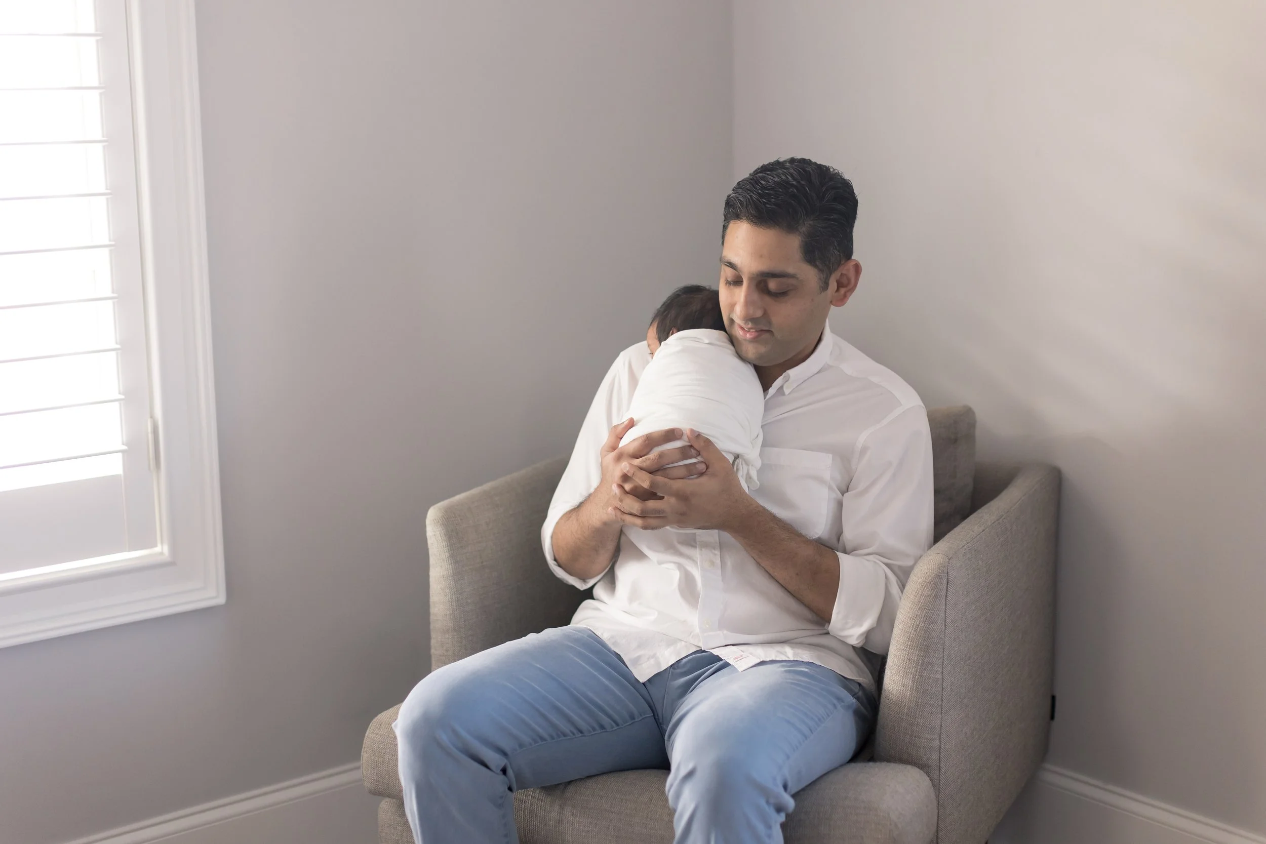 dad holding baby boy on his shoulder at their inhome newborn photography session in Evans, ga