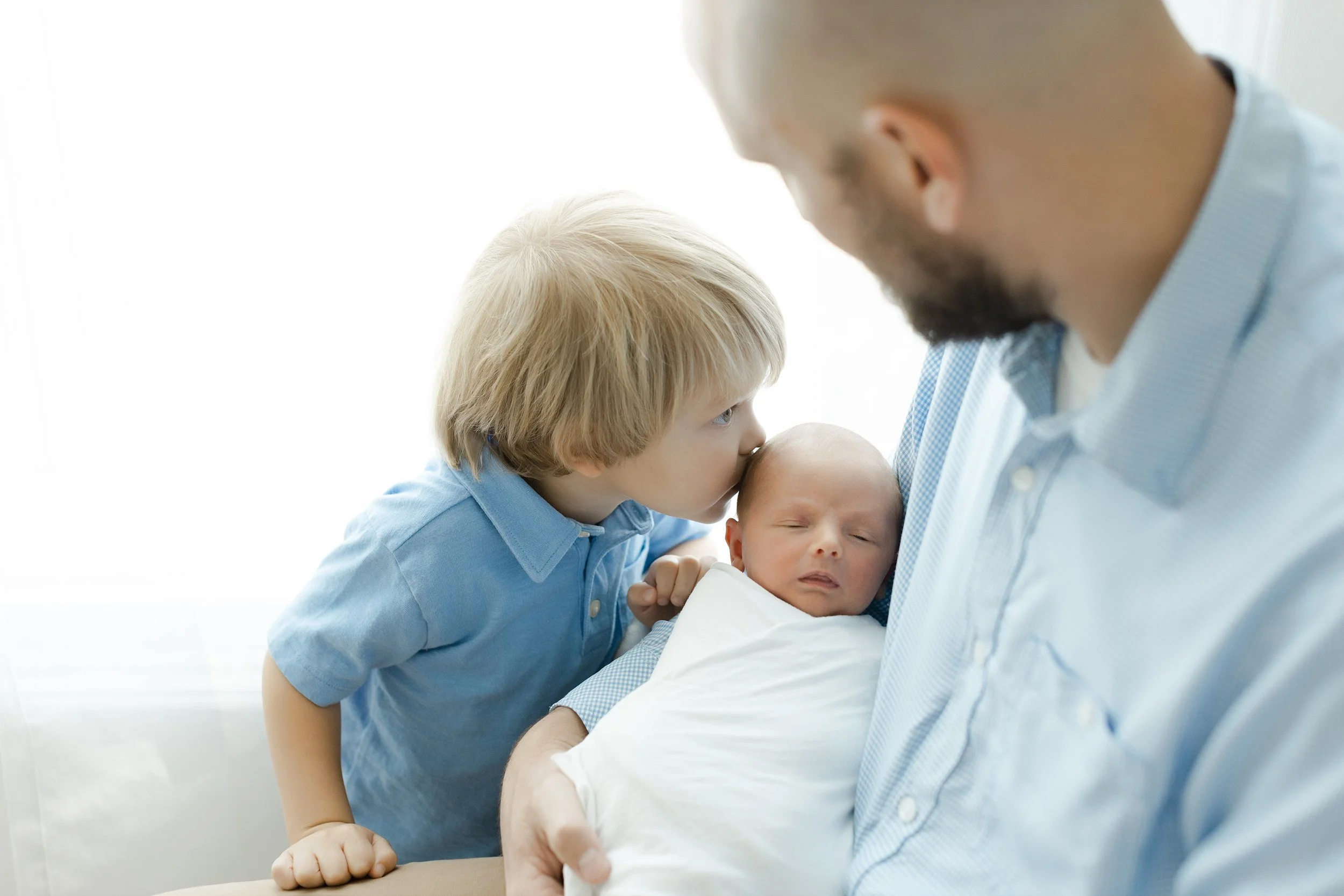 big brother giving newborn baby boy a kiss at their newborn photography session in Augusta ga