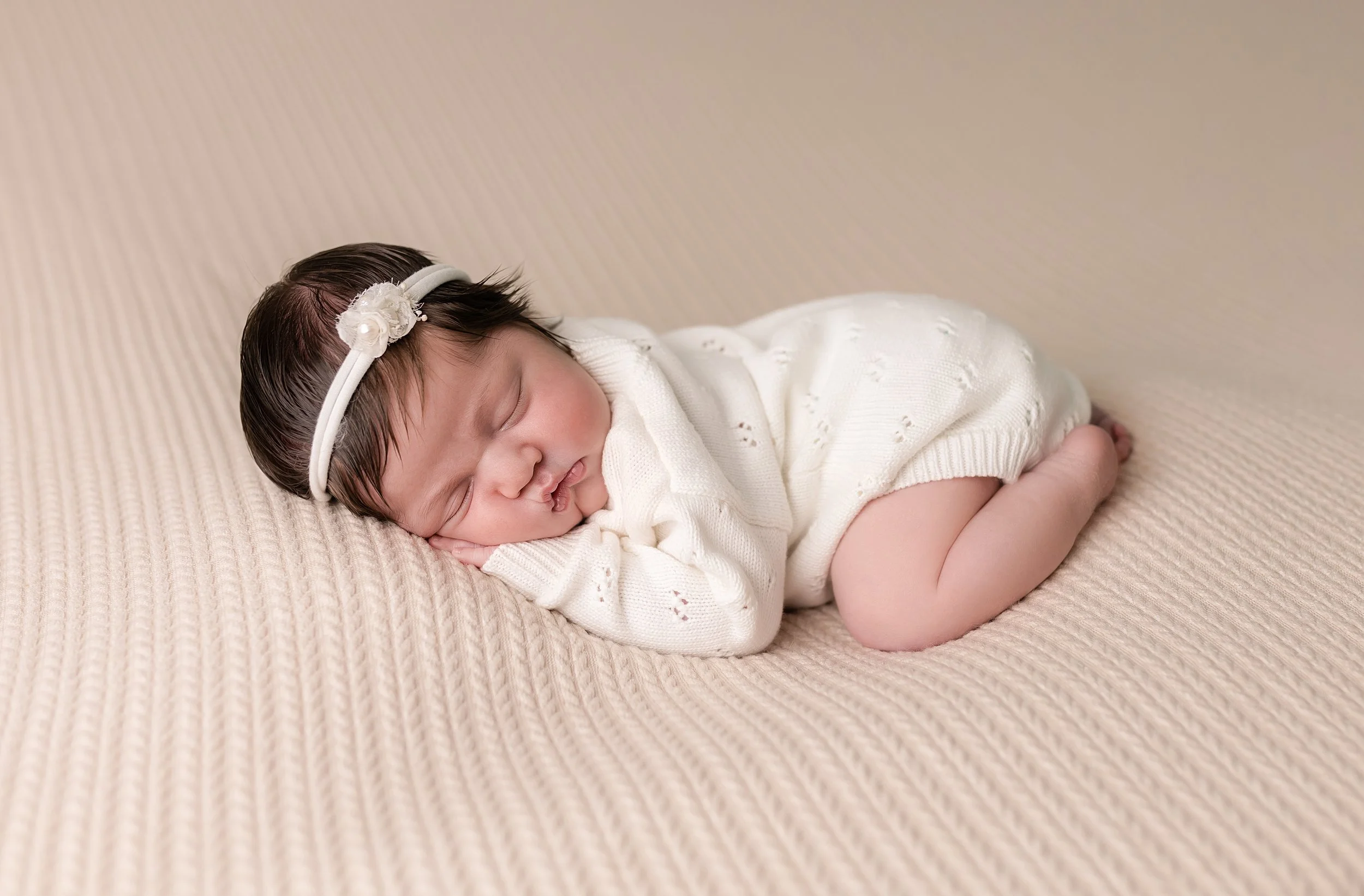 newborn baby girl posed on a bed at her newborn photography session in Augusta ga