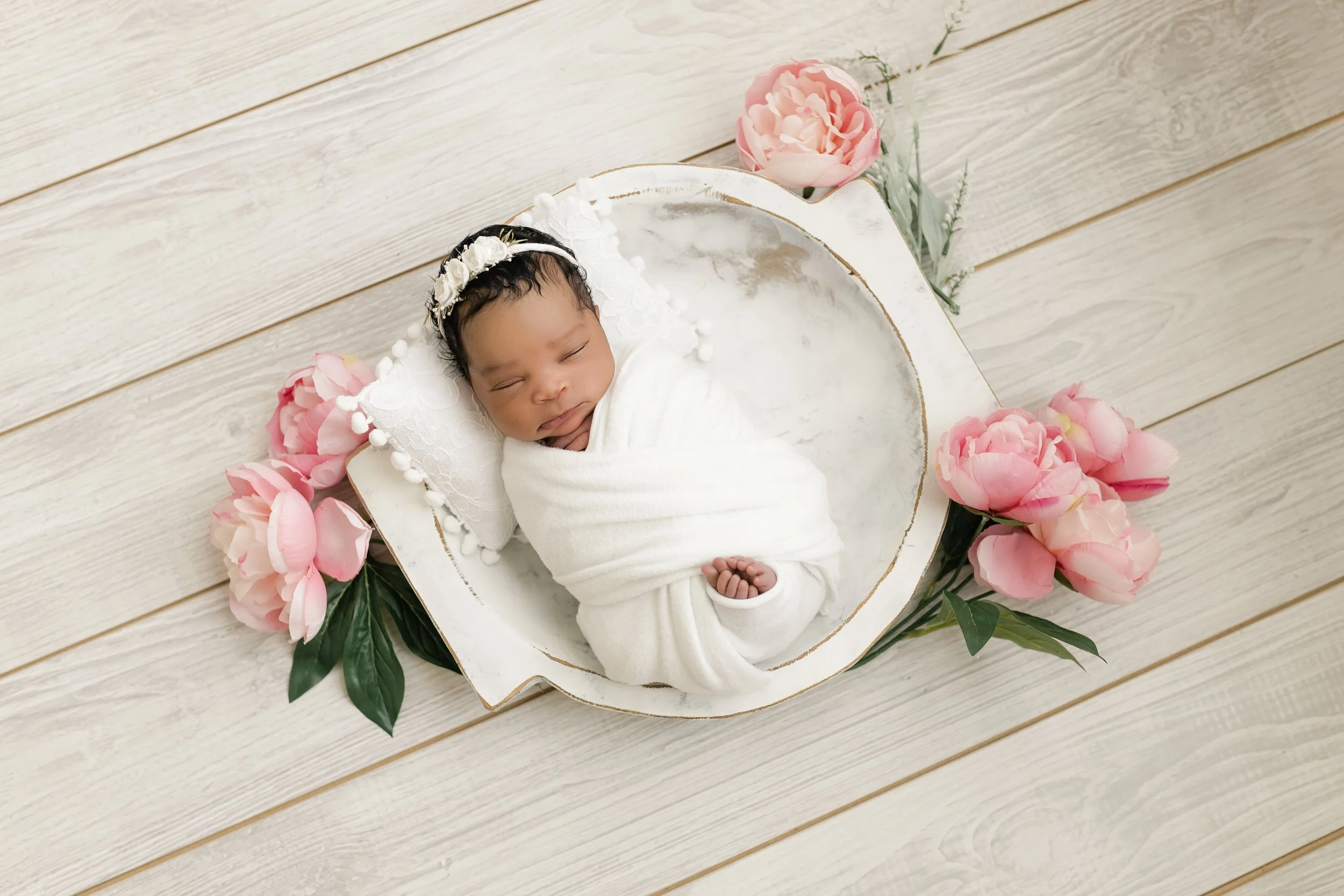 baby girl posing in a white bowl with flower embellishements at a Augusta ga newborn session