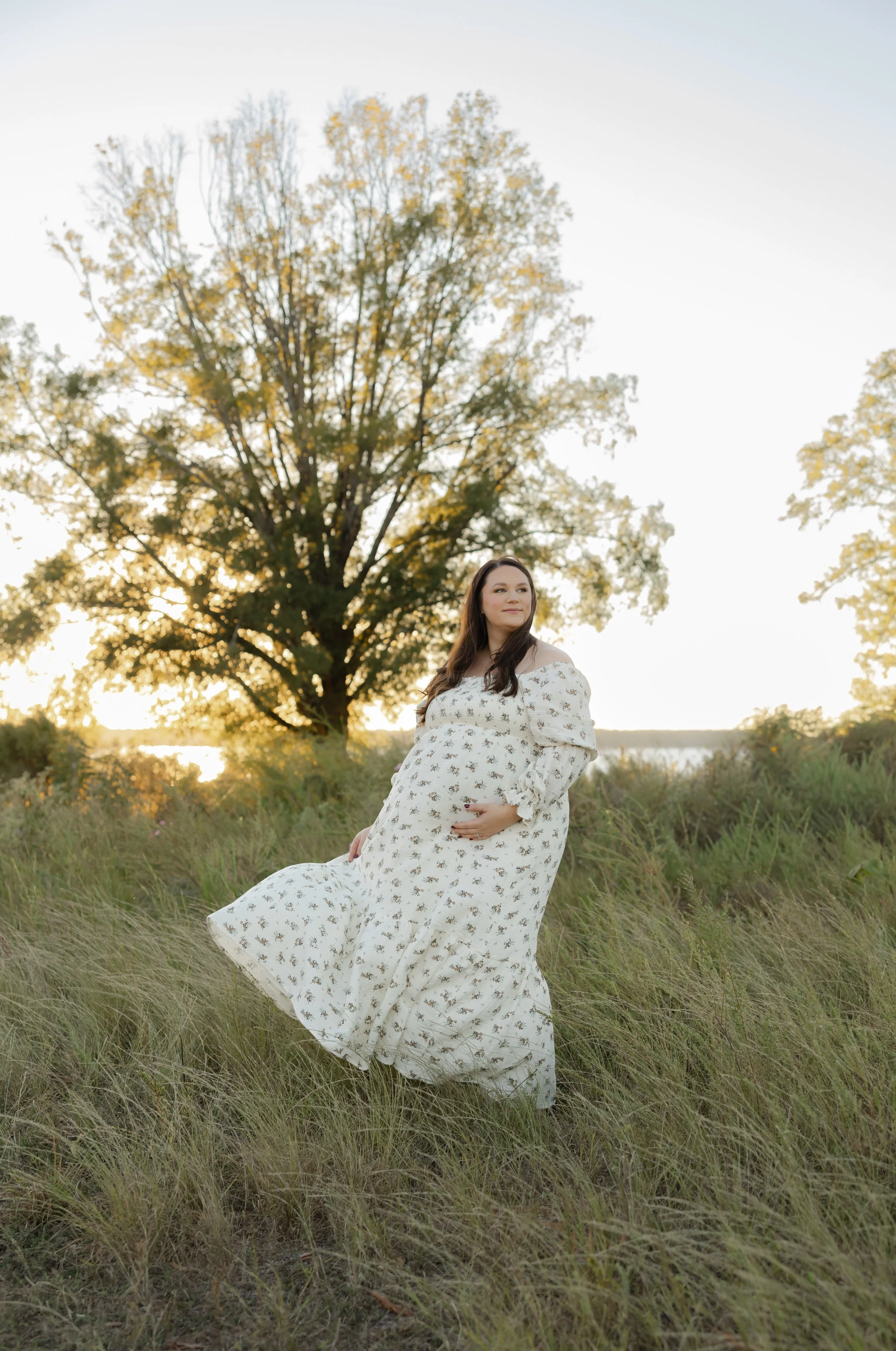 Pregnant mother in a floral maternity dress during golden hour at Clarks Hill Lake near Augusta Georgia