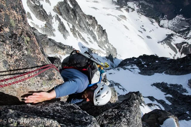 Trevor reaching for a good hand hold, high on the west ridge. The Stuart Glacier Couloir drops away below him.