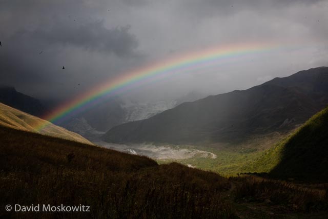 A rainbow straddles the mountain valley and snout of the valley glacier flowing off of the Shkhara massif. Georgian Caucuses Mountains.