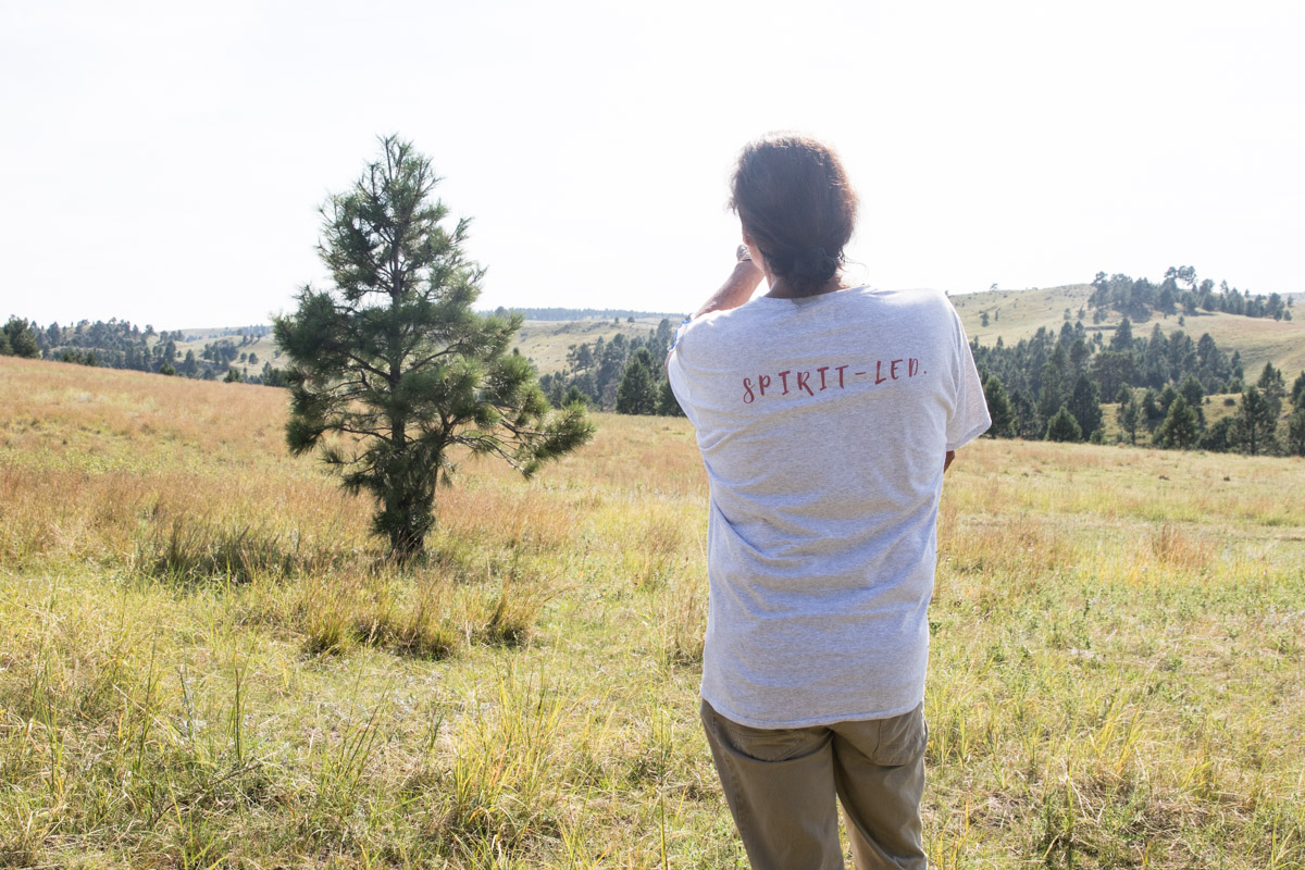 Dallas Chief Eagle looks out across Pine Ridge. One of the driving principles behind All Nations Gathering Center, written across the back of his shirt, is “Spirit Led.”
