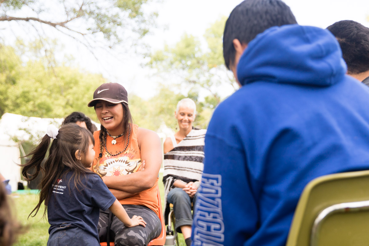  The daughter of one of the participants of the gathering joins the group of younger folks in the center of the circle for a moment of laughter. 