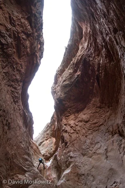 Canyoneer descending a deep limestone slot in Cove Canyon, Arizona.