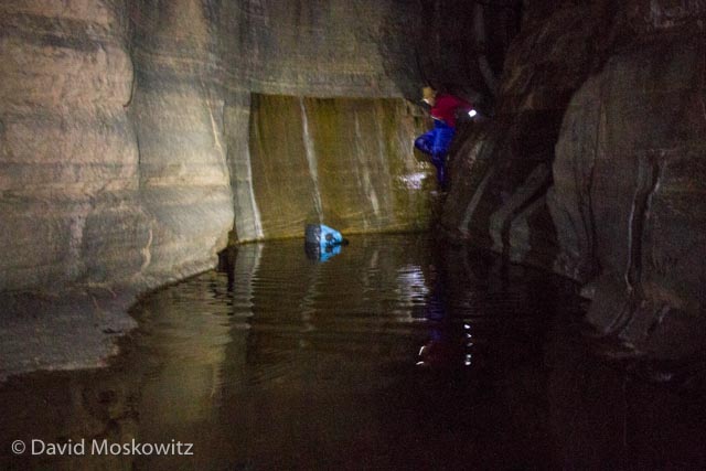  Downclimbing via headlamp light, Ian eases his way into the last pool of water, his dry bag floating nearby. 