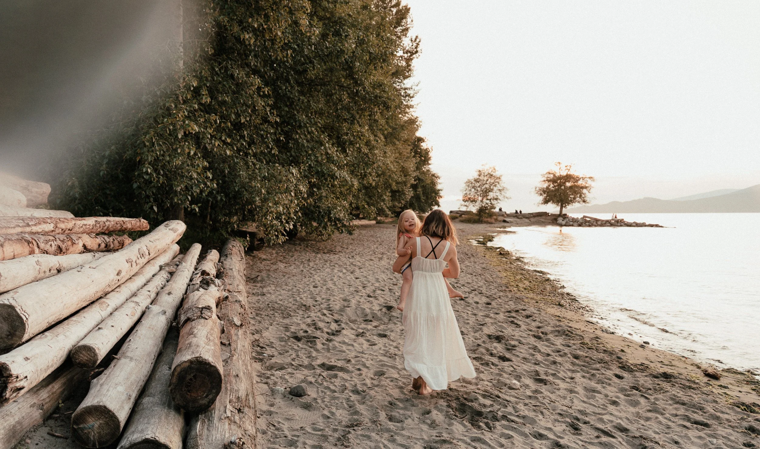 Mum and daughter on the beach of Vancouver, walking away.