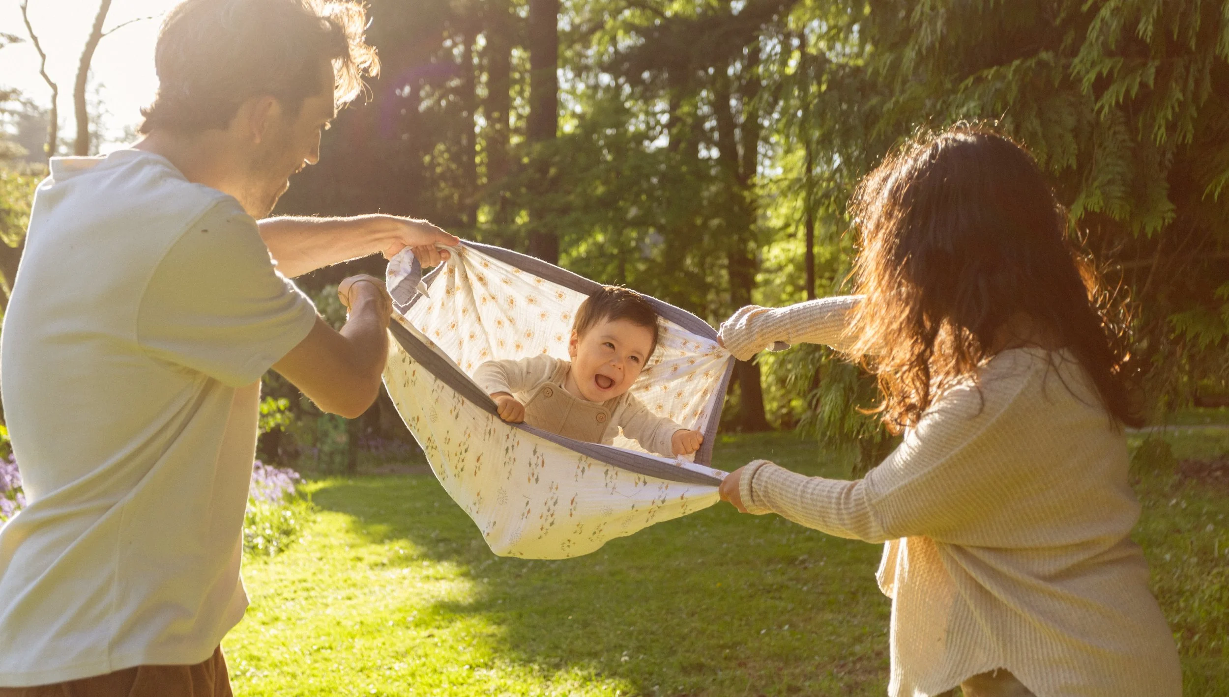 Mom and Dad giving baby a swing in Stanley Park