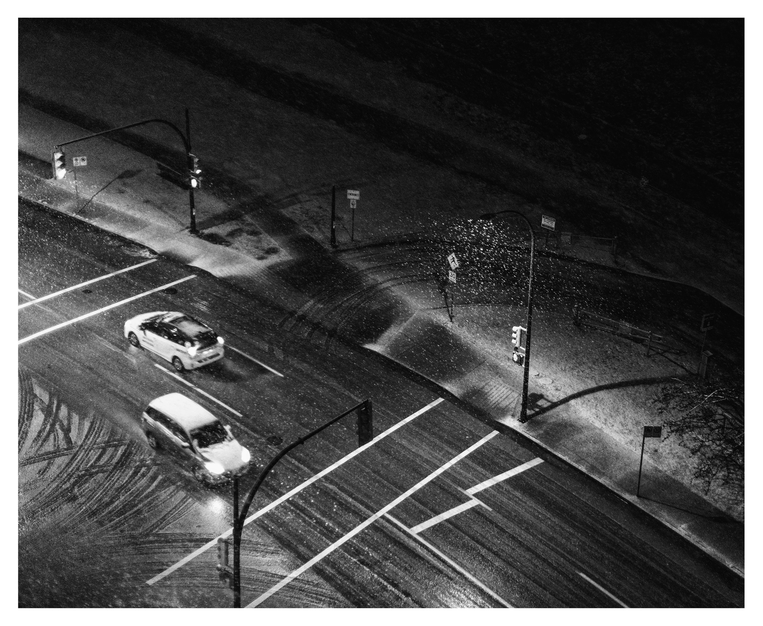         Snowfall at the intersection, a study in light, movement, and silence.