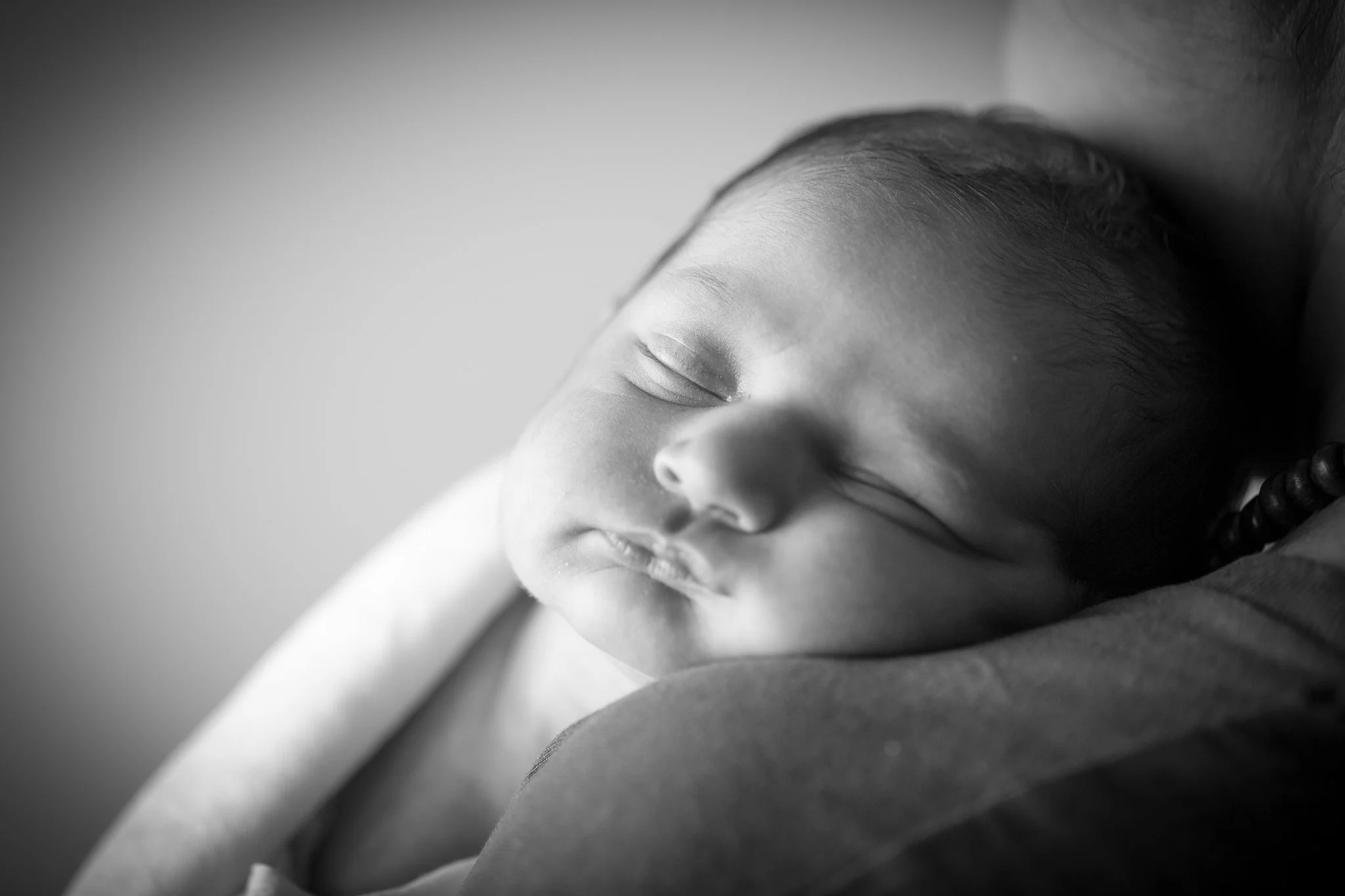 Photograph of a baby sleeping on her mum's shoulder