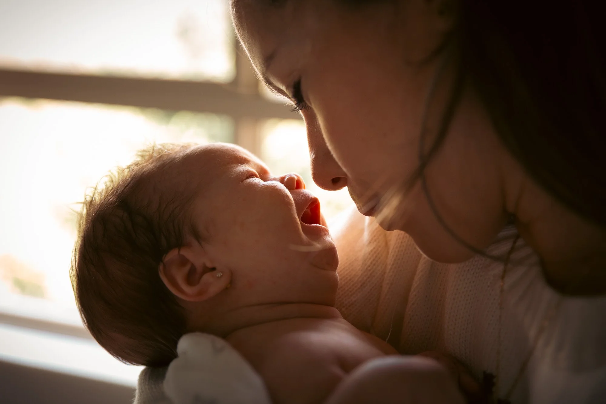 A close up of newborn baby in her Mom's arms