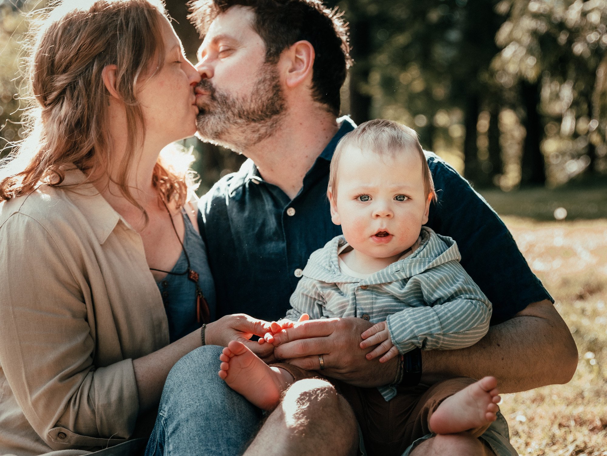 Mom and Dad kissing with the baby on the lap