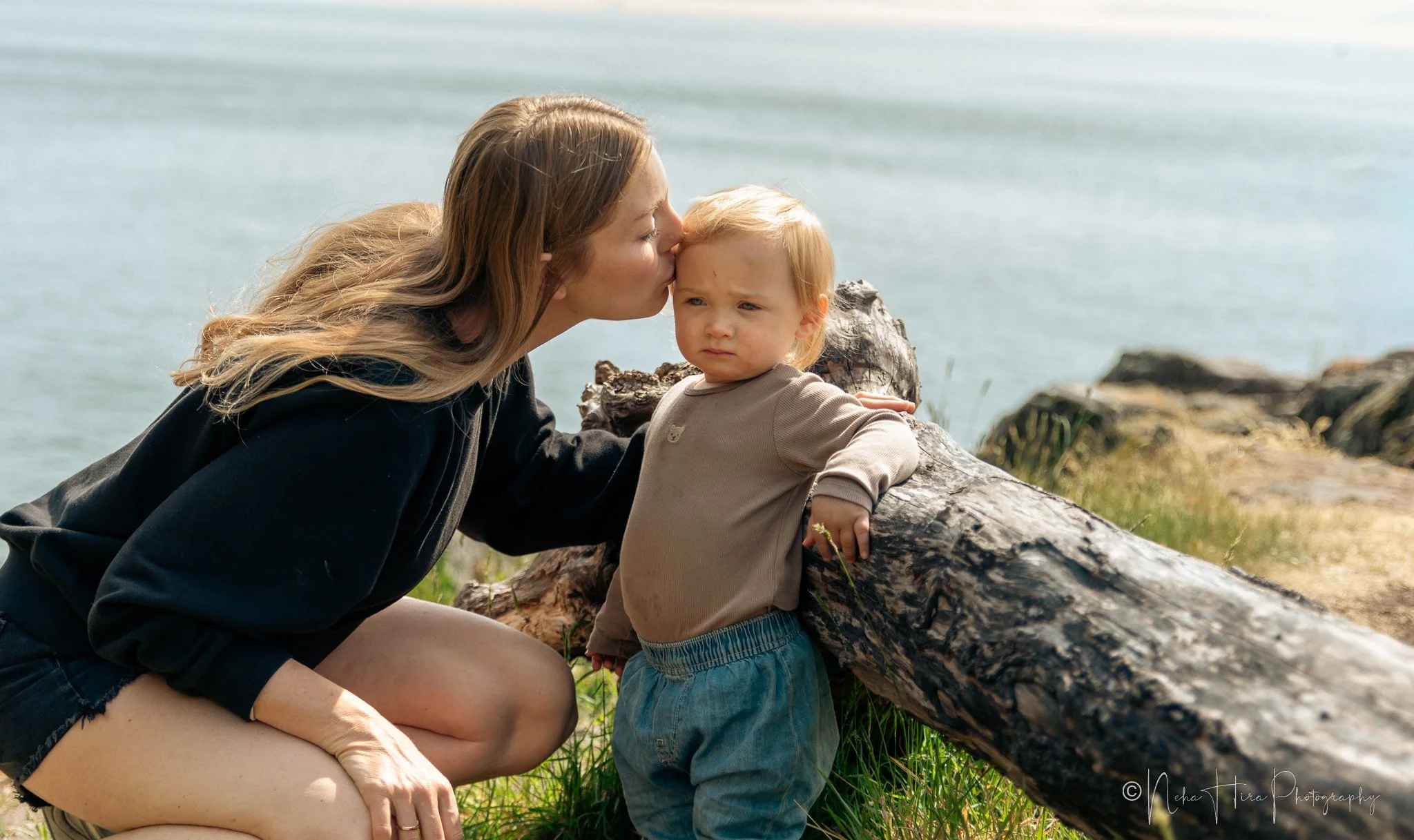 Mother kissing toddler daughter's forehead on coastal rocks at Juniper Point, Lighthouse Park West Vancouver