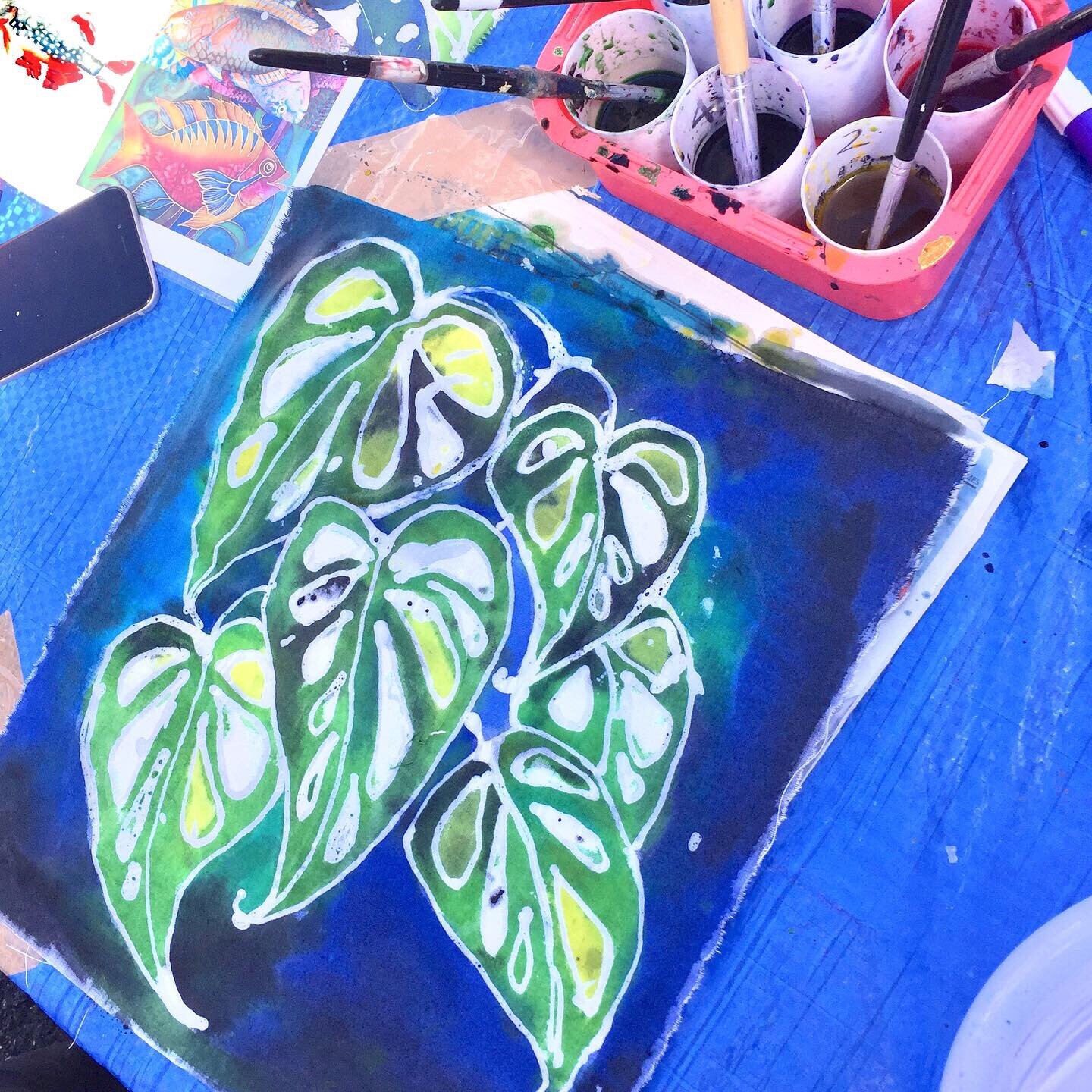 Textile workshop batik hot wax drawing and dyes of leaves on blue background