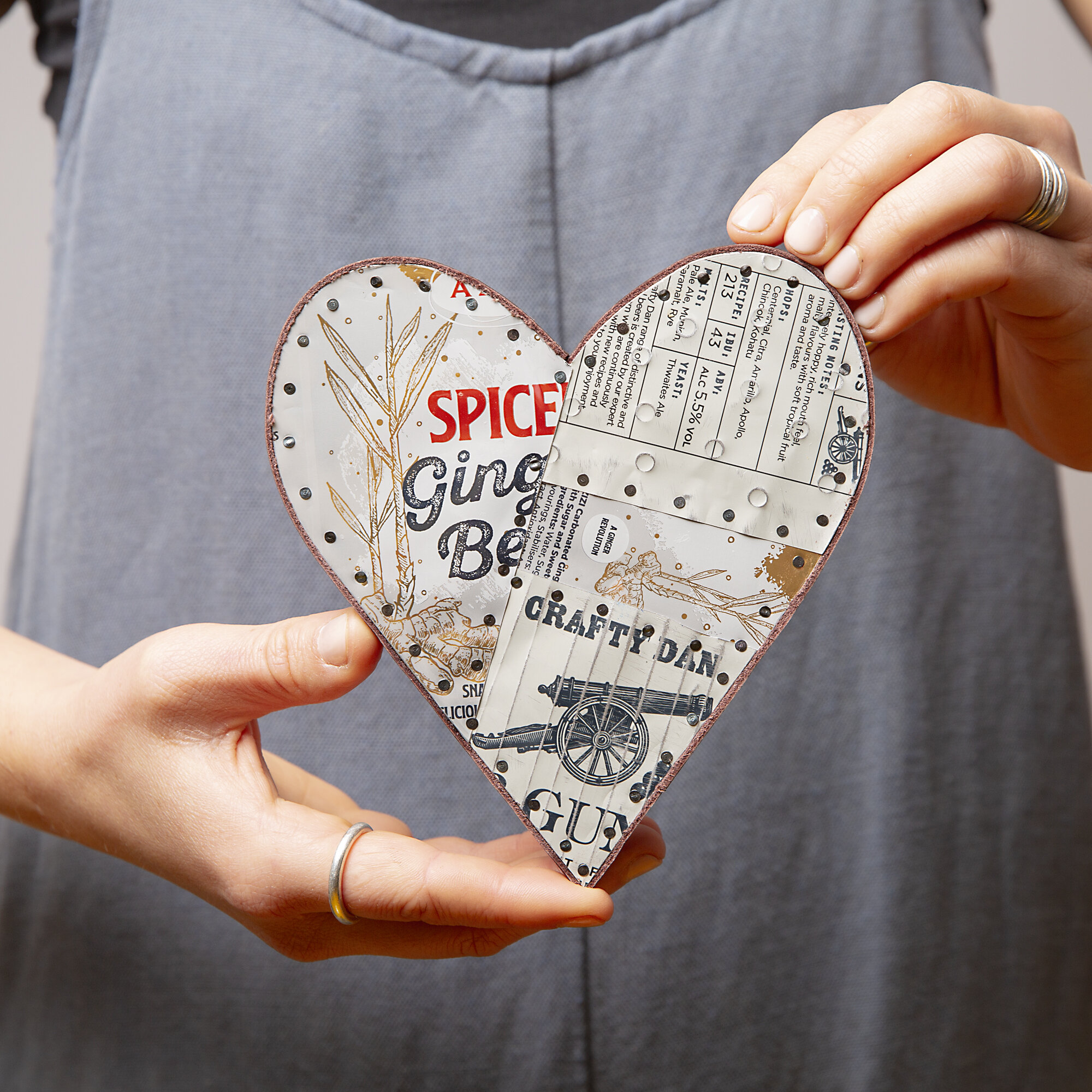 woman holding a white drinks can metal decorative heart that she has made