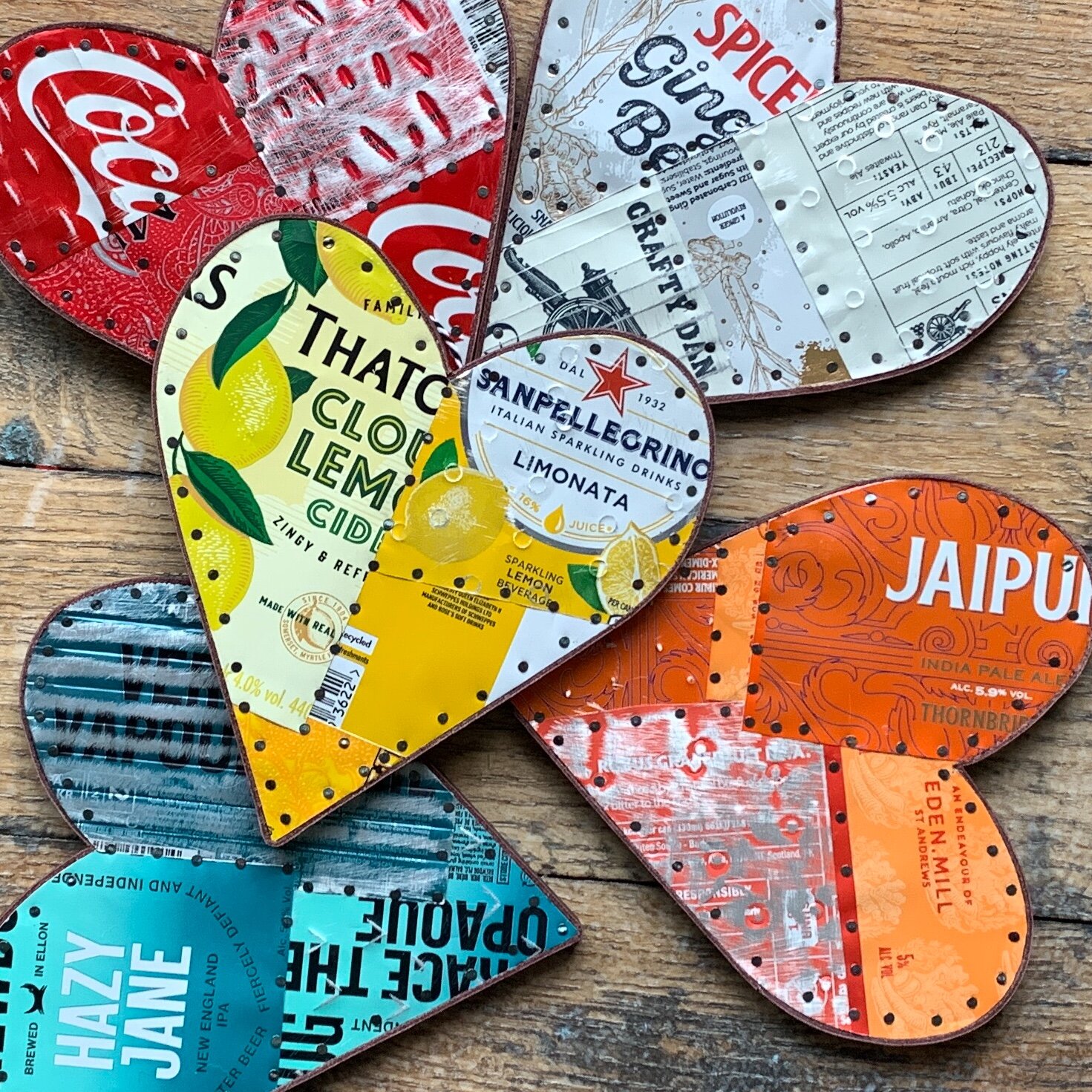A collection of five different drinks can metal hearts resting on a table Red white orange yellow blue