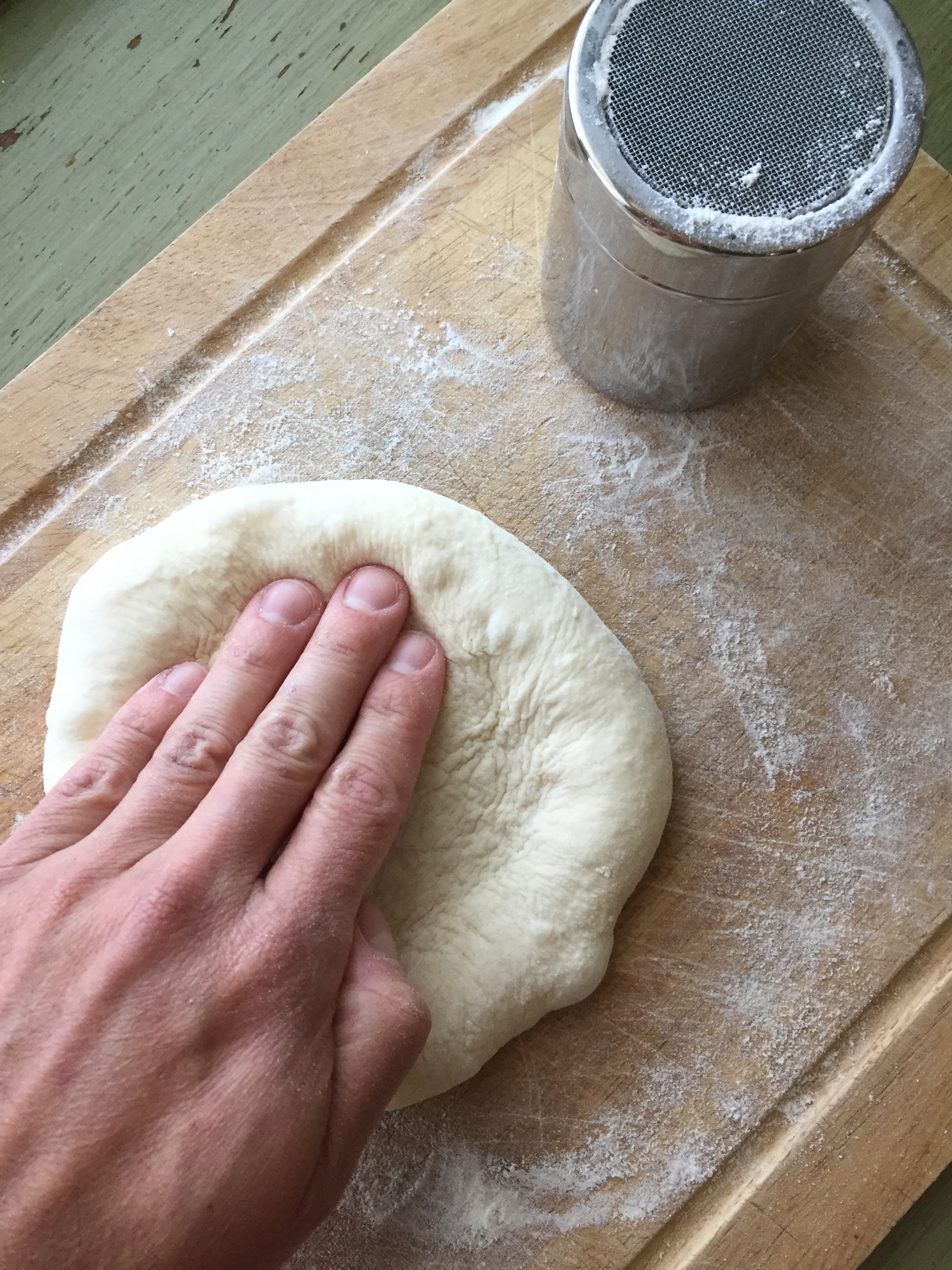  To shape your dough, start by pressing your fingers down around the edge to create the crust.  