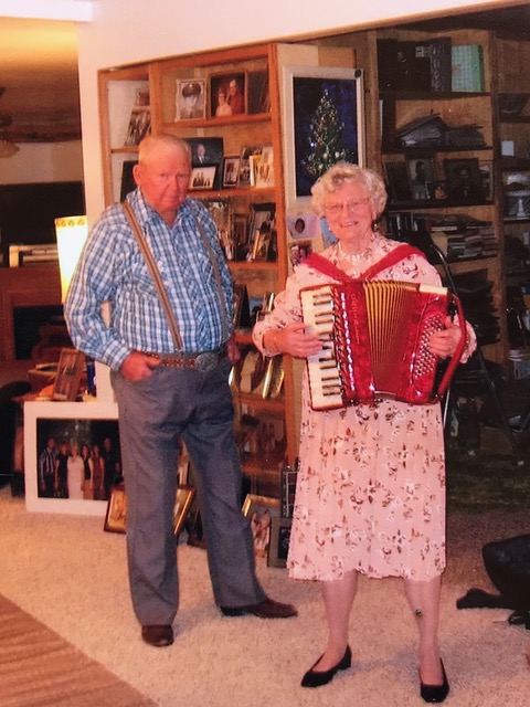 Celia Sandoz Ostrander Barth plays her prized Swiss accordion in her living room while husband Lyle looks on