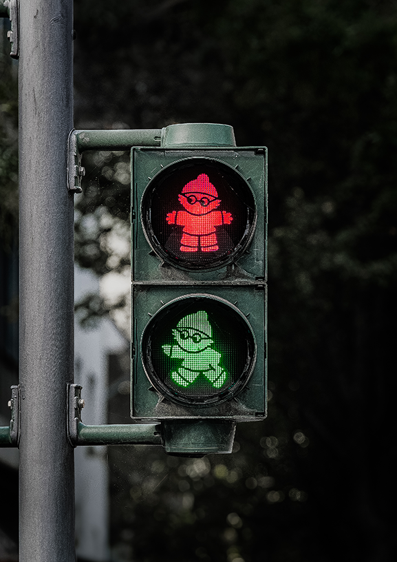 A playful, graphic capture of a stylized pedestrian traffic signal in Frankfurt, Germany. The glowing red and green figures pop brilliantly against a dark, moody background. Perfect for adding a quirky touch of European city charm and vibrant color t