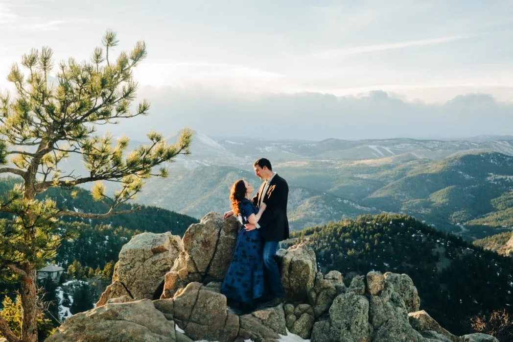 couple embracing on top of a mountain with a huge Rocky Mountain landscape view.jpg