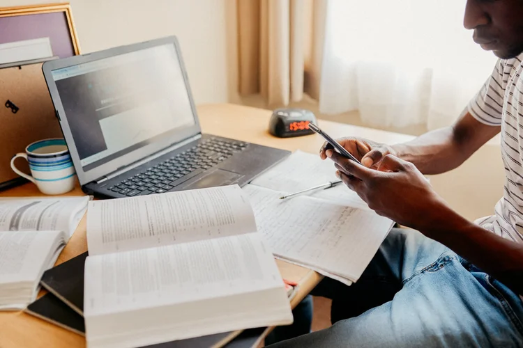 black student studying for the LSAT with books and notes next to his laptop