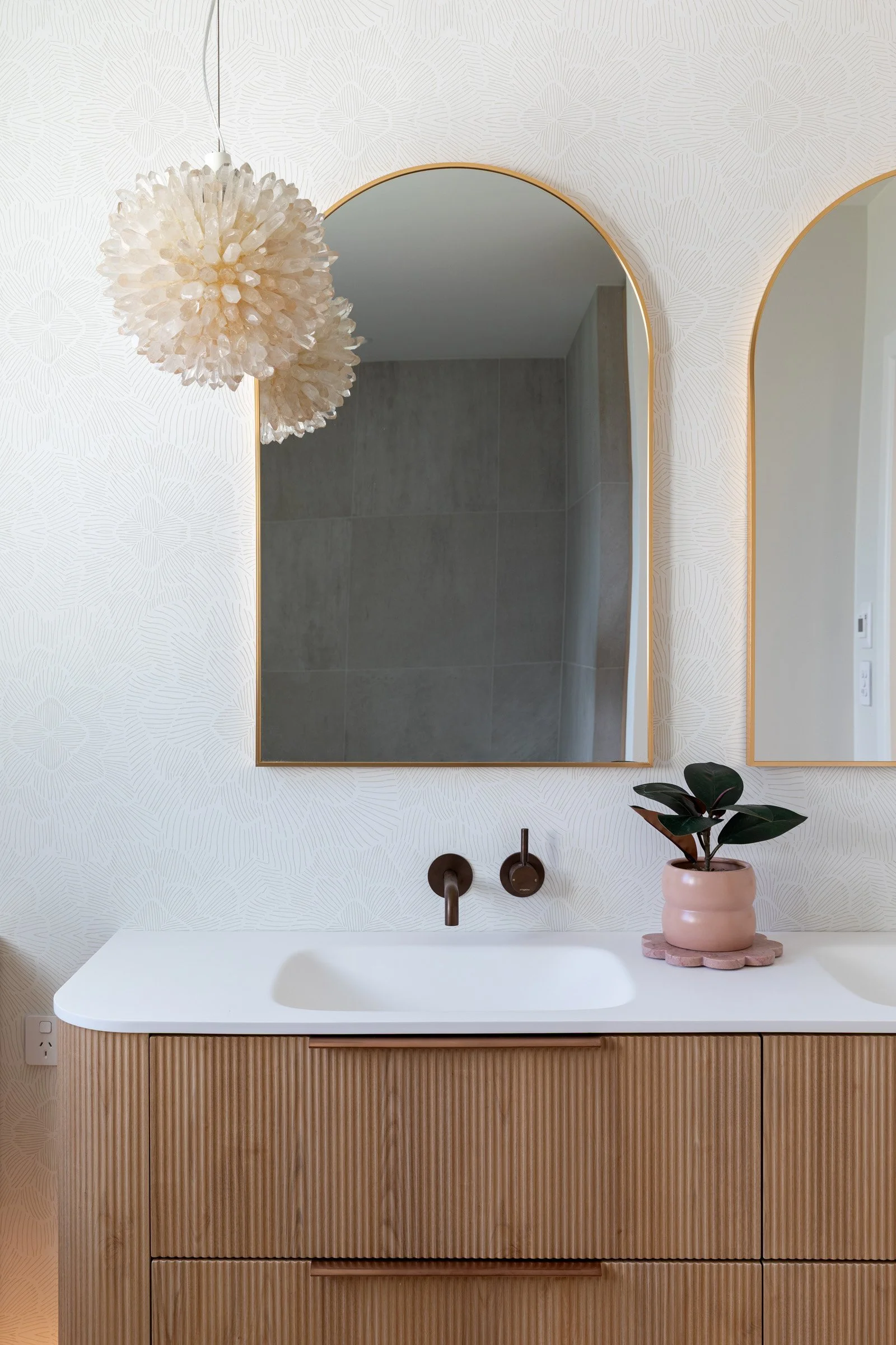 Bathroom with arched brass details and curved custom vanity