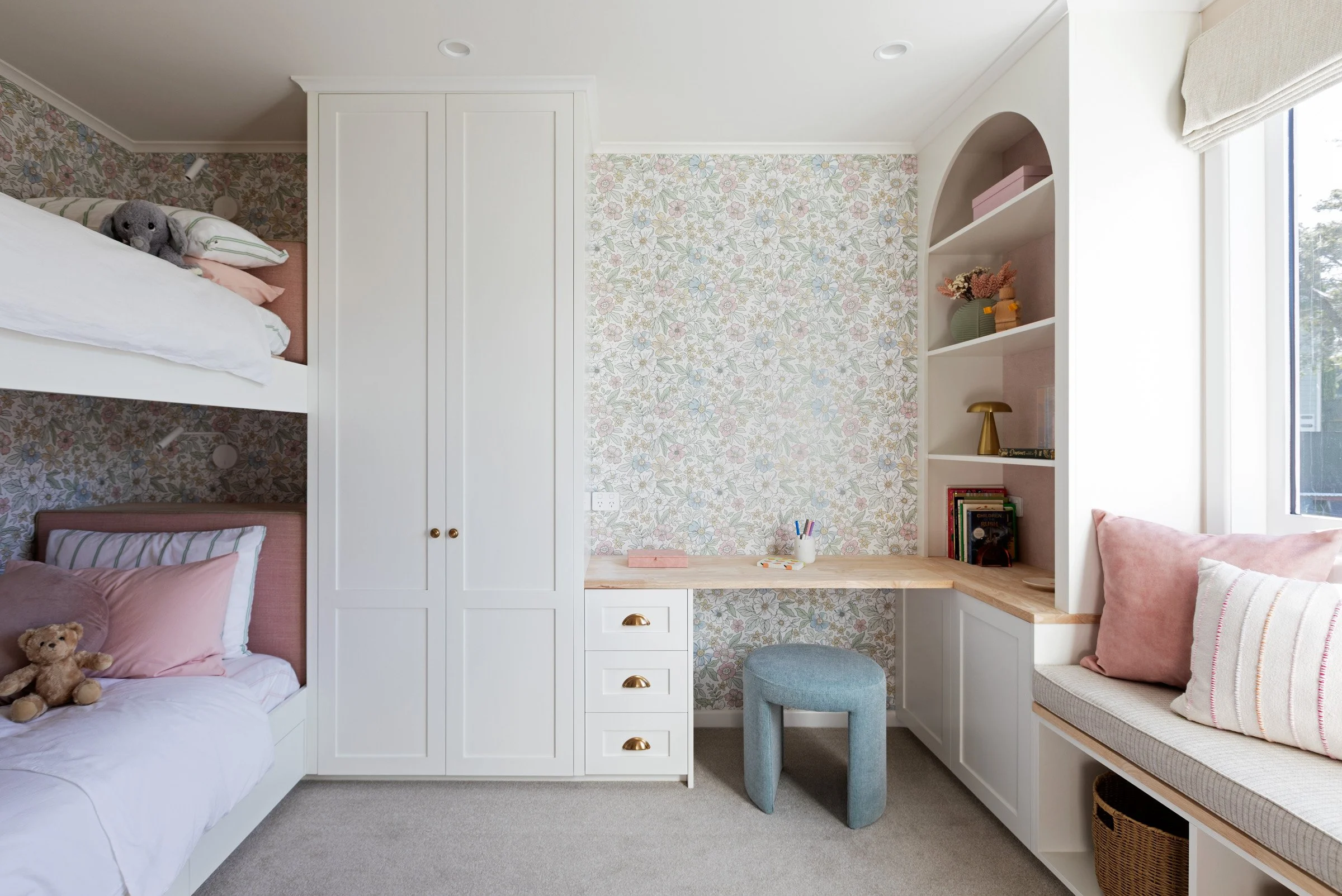 Girl's bedroom with floral wallpaper and curved bookcases