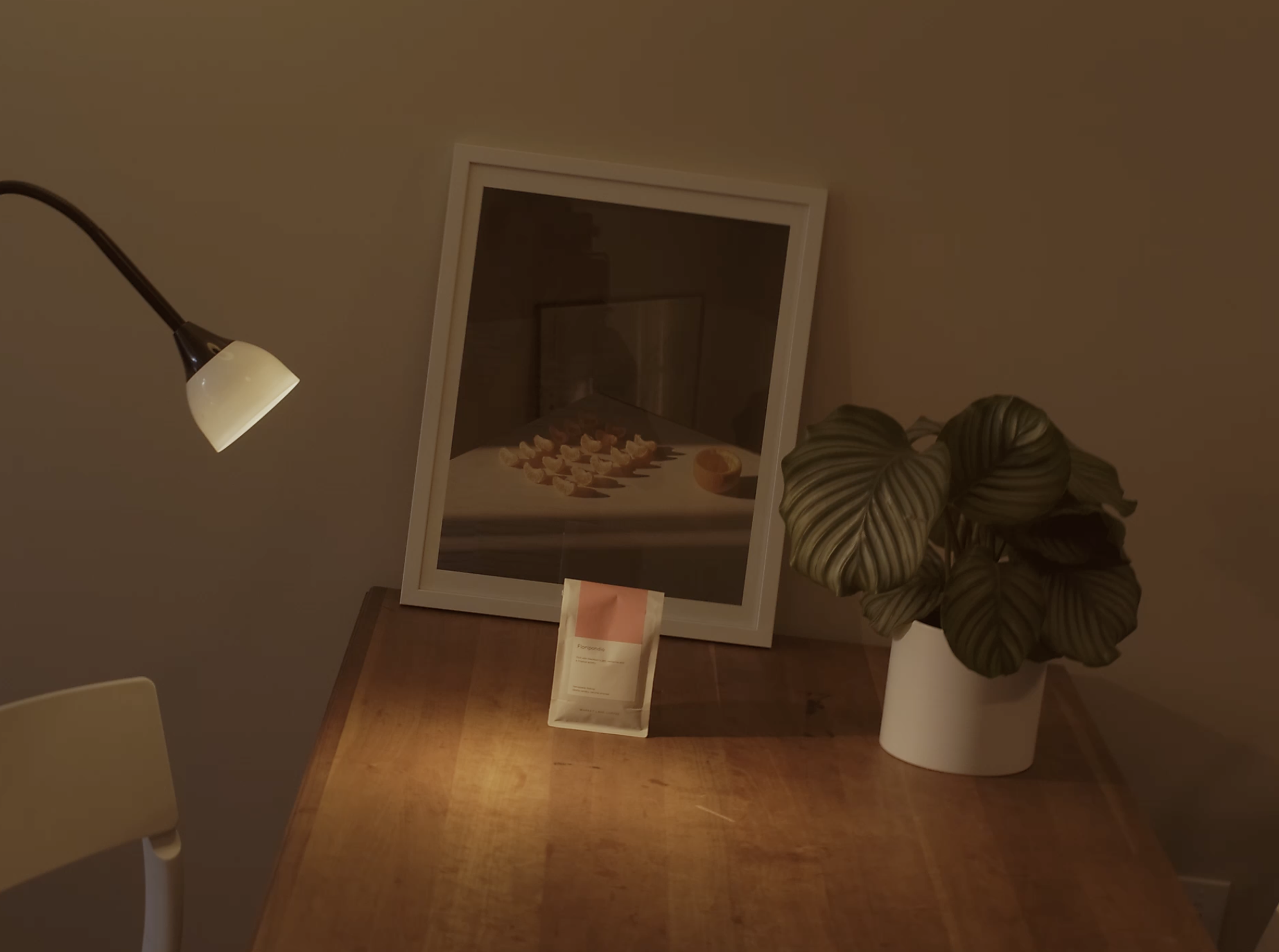 A wooden table with a large mirror leaning against the wall, next to a potted plant with large, green, striped leaves, and a floor lamp with a white lampshade turned on.