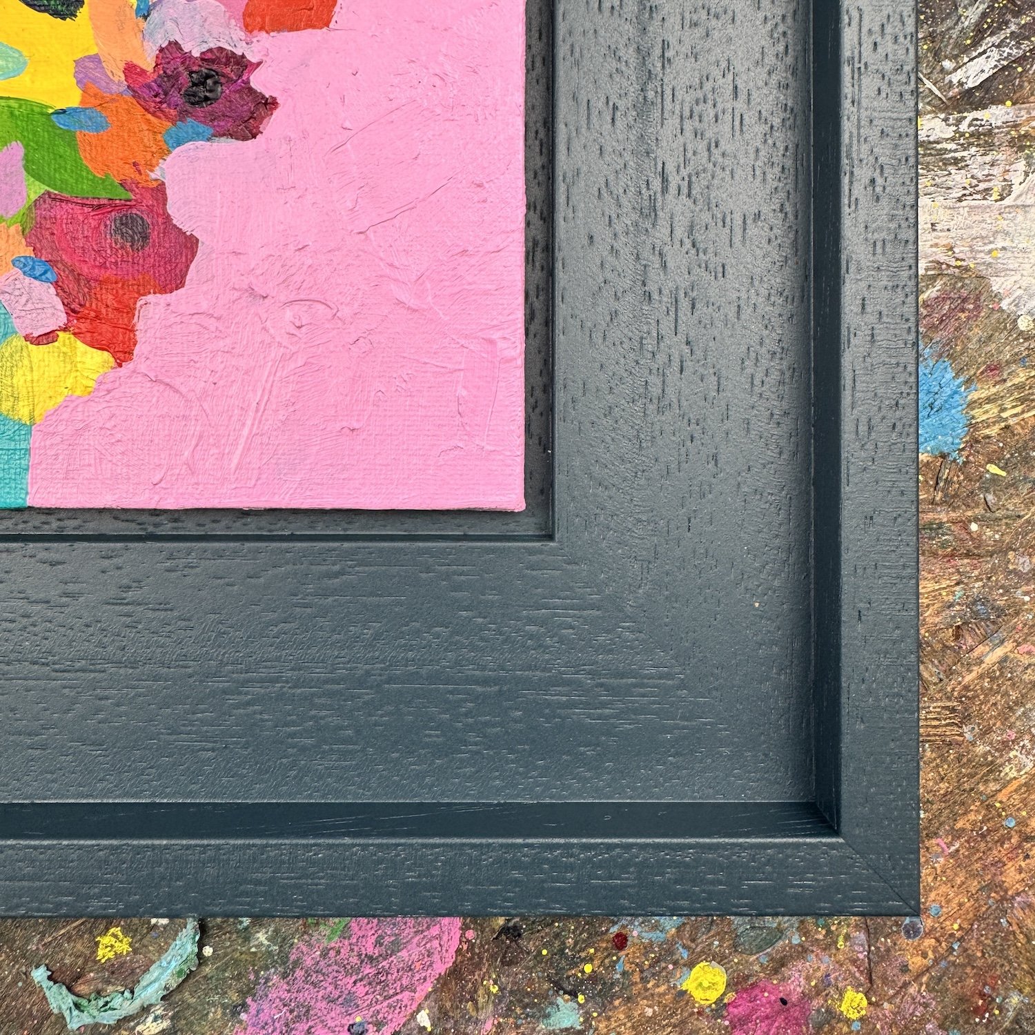 Detail of layered paint and loose marks in a small vibrant floral artwork, yellow and red blooms on pink