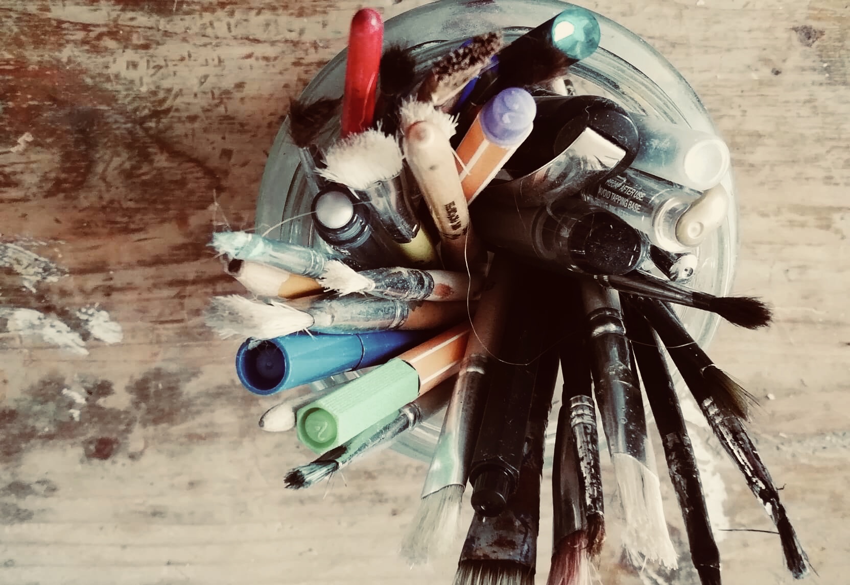 Glass with pencils an pens on a wooden table