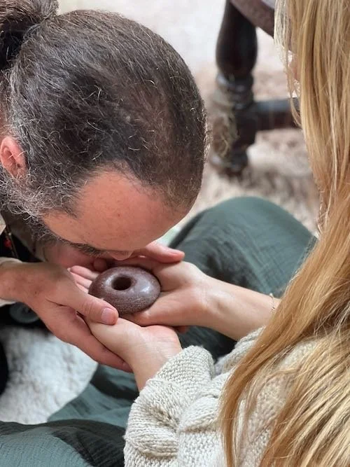 Shamanic teacher Alku, blowing on a pi stone of the Munay-Ki initiation rites, in the open hands of a blonde woman, Aynua Amazonas, Peru