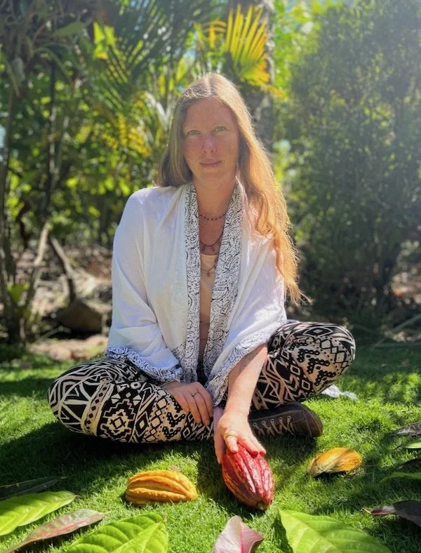Diana, co-founder of Aynua Amazonas, sitting on the ground of a cacao forest, touching a cacao pod, in Northern Peru