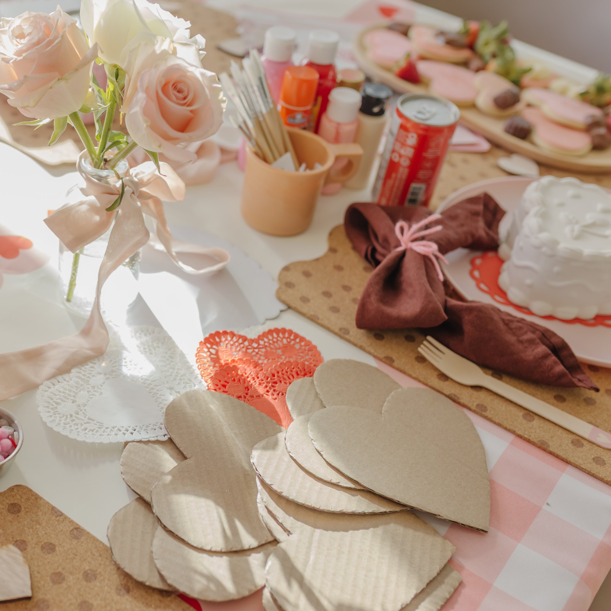instructions on how to make your own heart-shaped valentines day collage art project, using cardboard, heart-shaped doilies, crepe streamers, stickers and yarn.