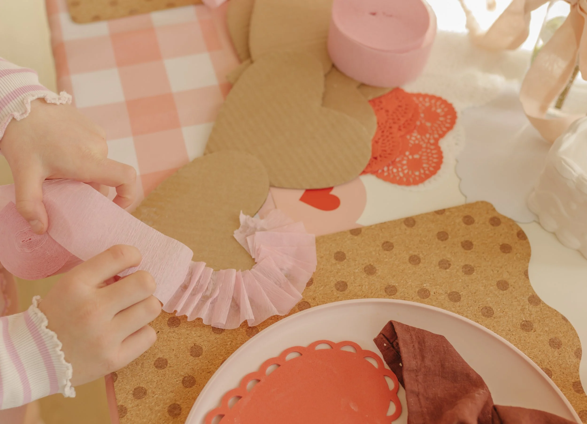 instructions on how to make your own heart-shaped valentines day collage art project, using cardboard, heart-shaped doilies, crepe streamers, stickers and yarn.