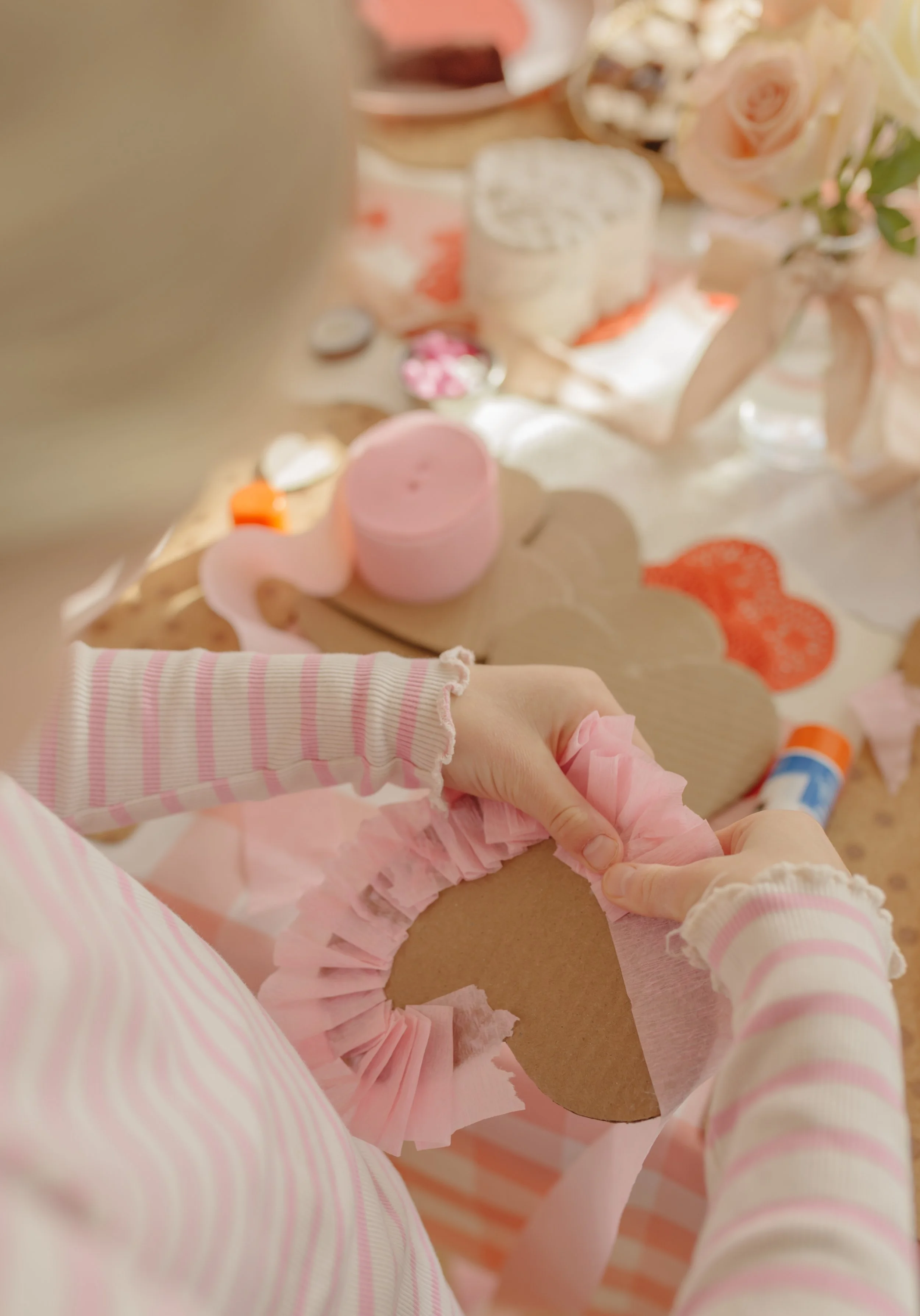 instructions on how to make your own heart-shaped valentines day collage art project, using cardboard, heart-shaped doilies, crepe streamers, stickers and yarn.