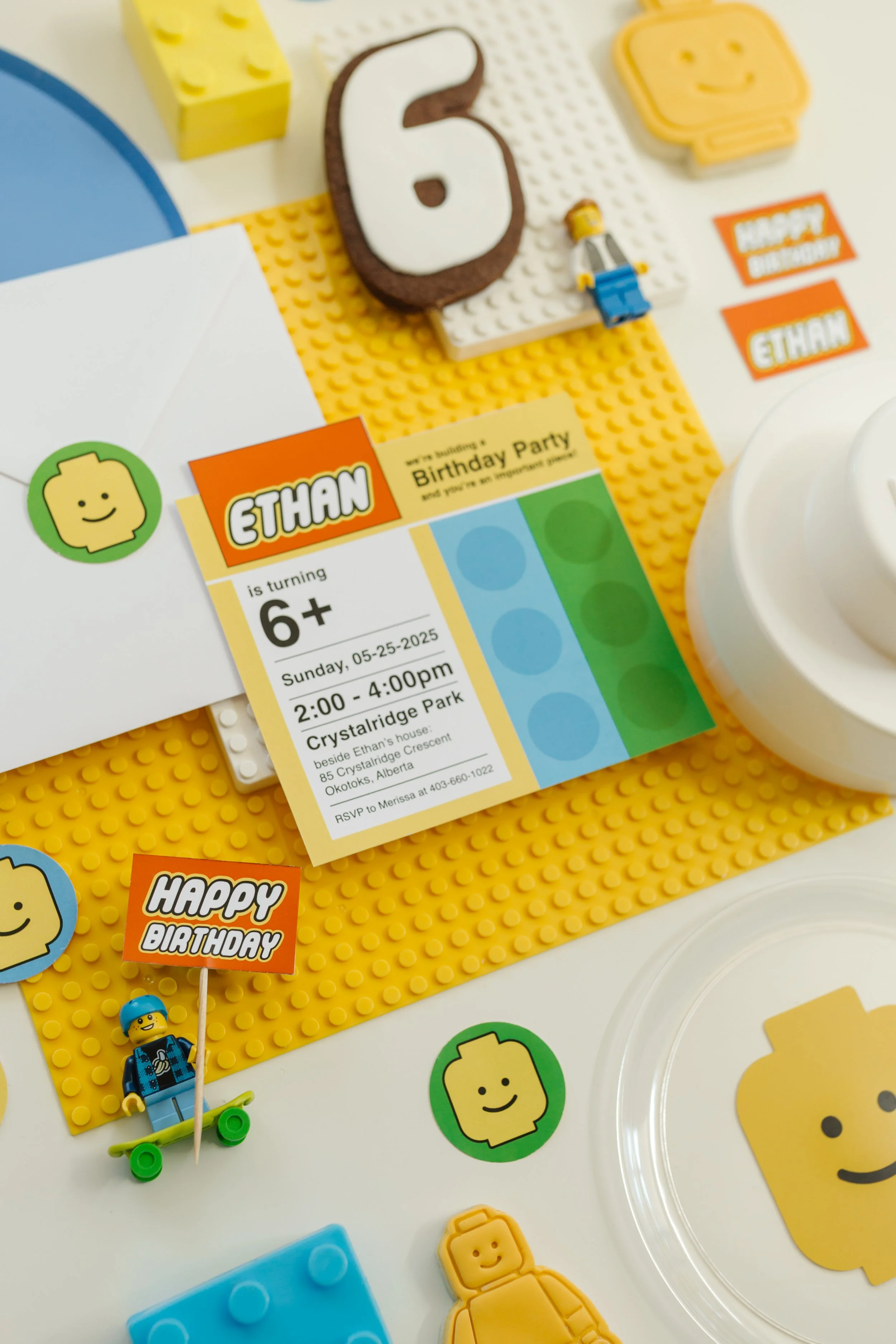 Lego-themed birthday party invitation surrounded by Lego blocks, stickers, and decorations in bright colors.