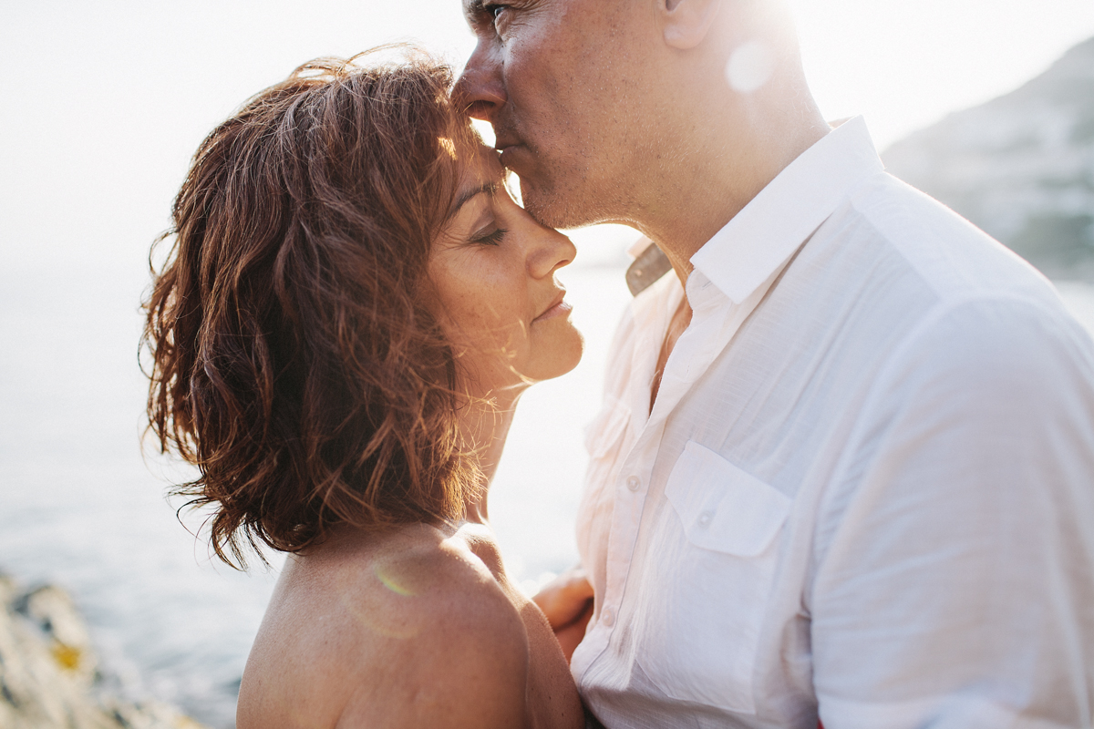 Man kissing woman on her forehead in front of the sea